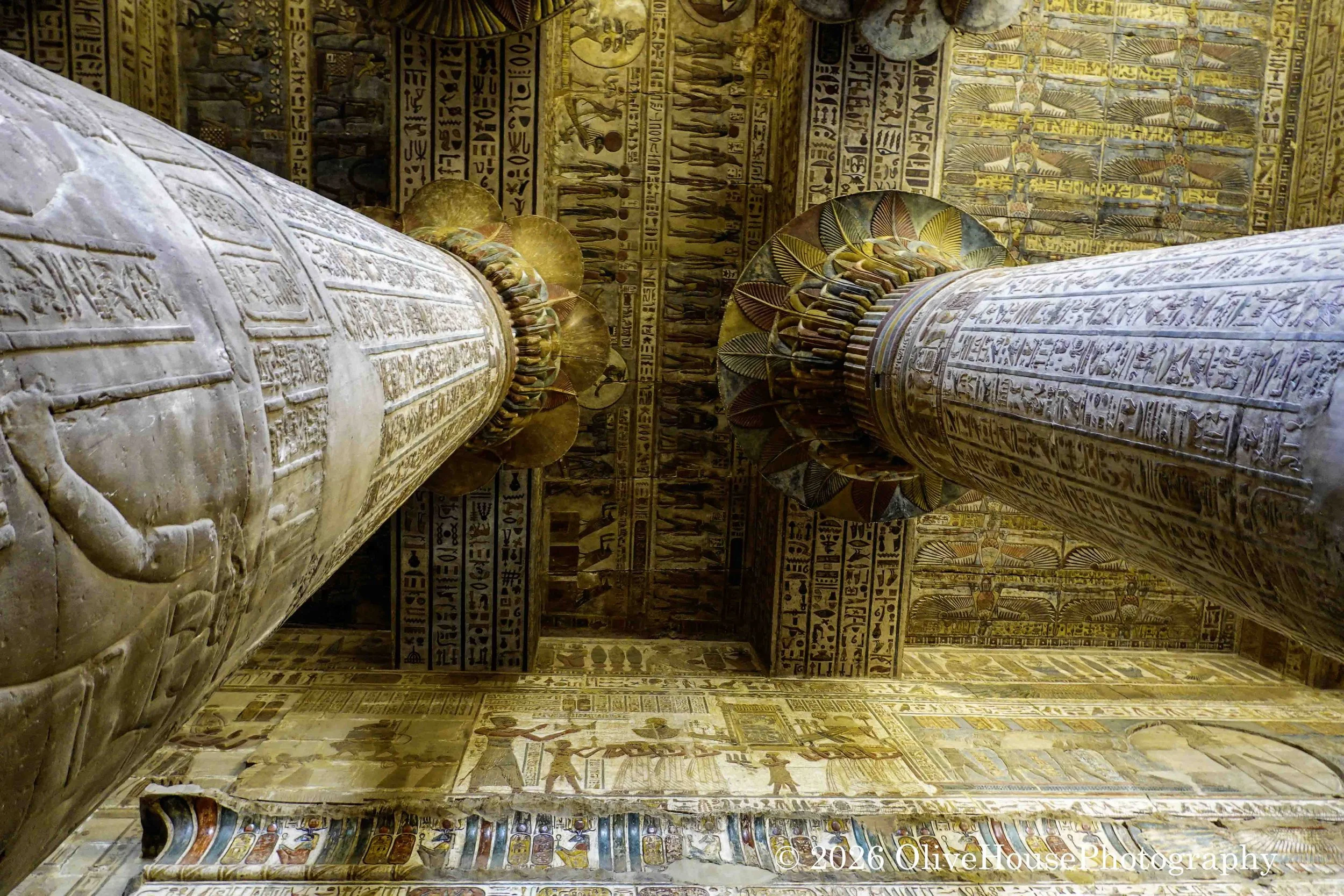 Well-preserved hypostyle hall of the Temple of Khnum in Esna, Egypt, featuring 24 massive columns restored to remove centuries of soot, with intricate floral capital reliefs of celestial scenes, including deities and astronomical symbols.