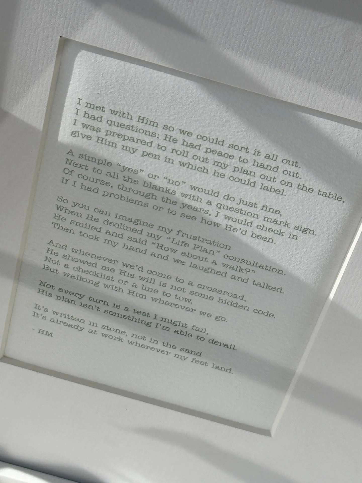 Close-up of a framed, printed text on a white background inside a white frame. The text is a story or a poem, with some words in italics.