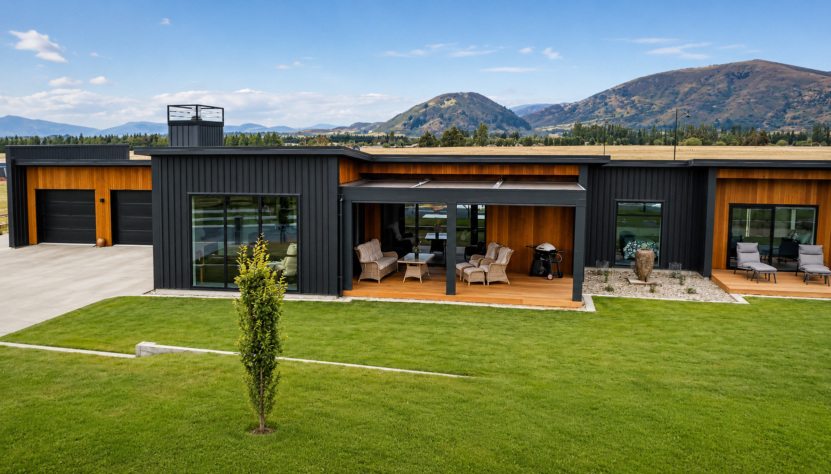 Modern residential building with wooden and black metal exterior, landscaped plants, and a paved walkway at sunset. South Island property development.