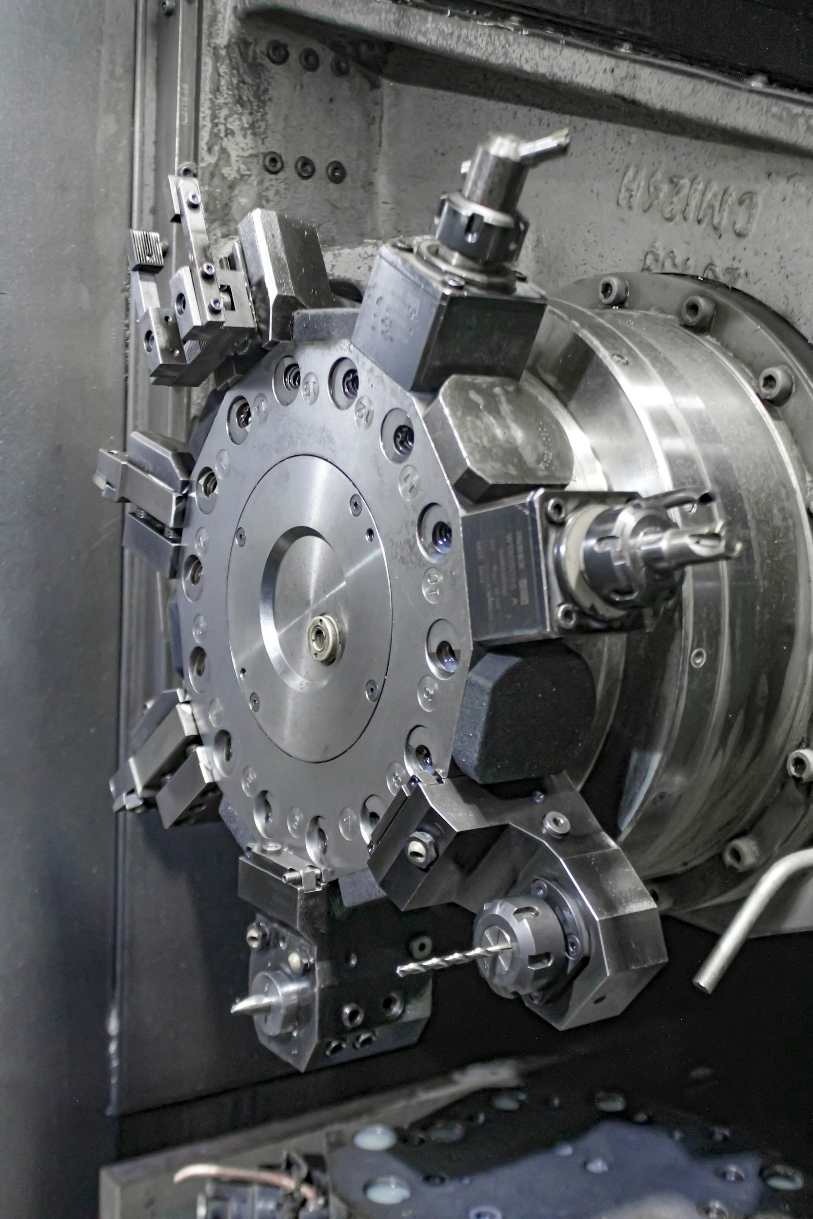 Close-up of a CNC machine spindle with a drill bit attached, showing metal parts and mechanical components.