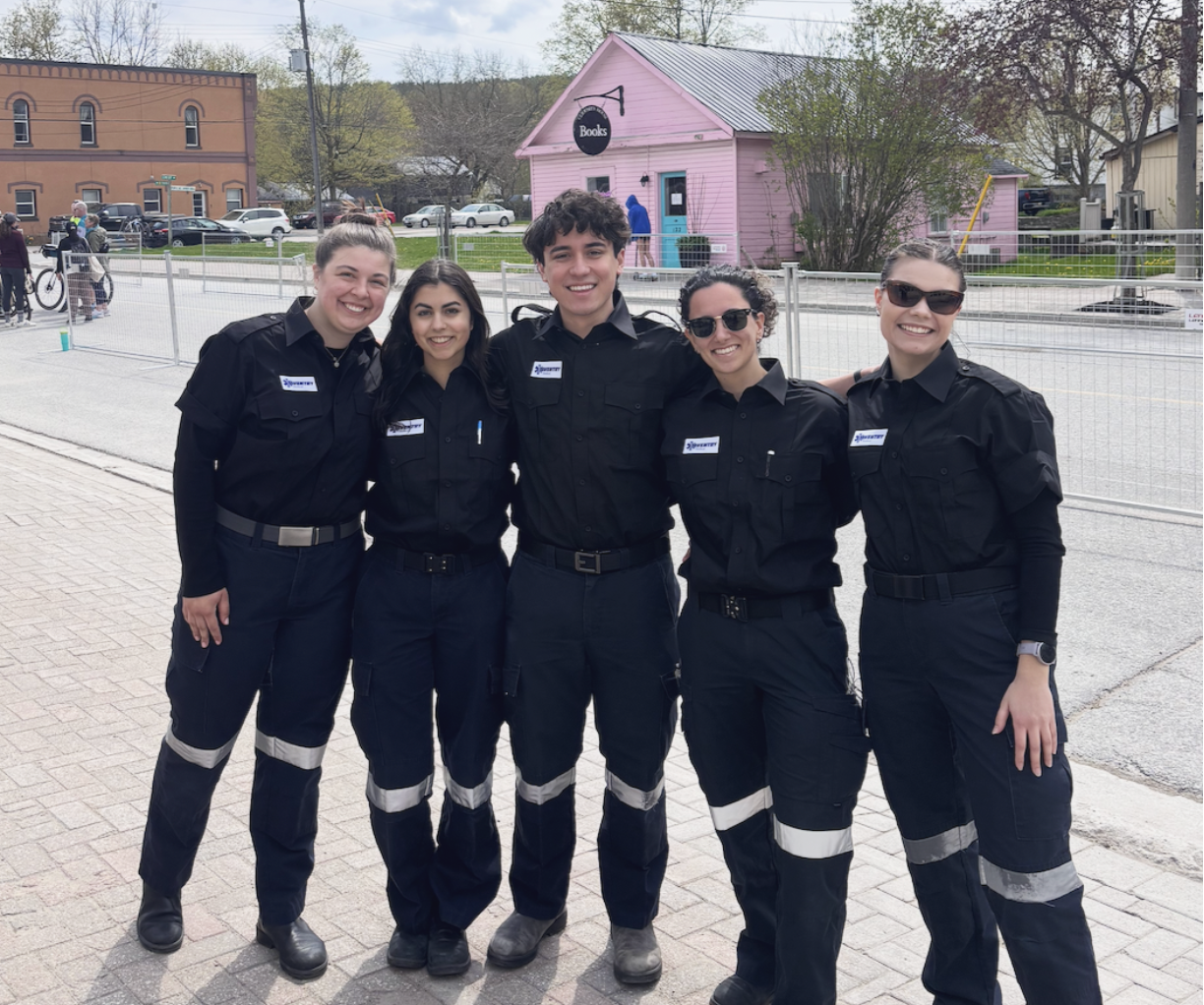 Five smiling Aventry emergency responders in uniform standing outdoors with arm around each other