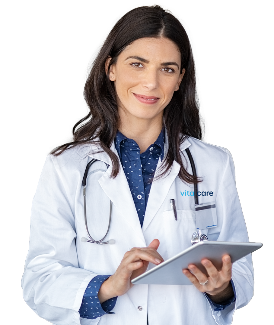 A female doctor with long dark hair, wearing a white coat with a stethoscope around her neck, holding and using a tablet device.