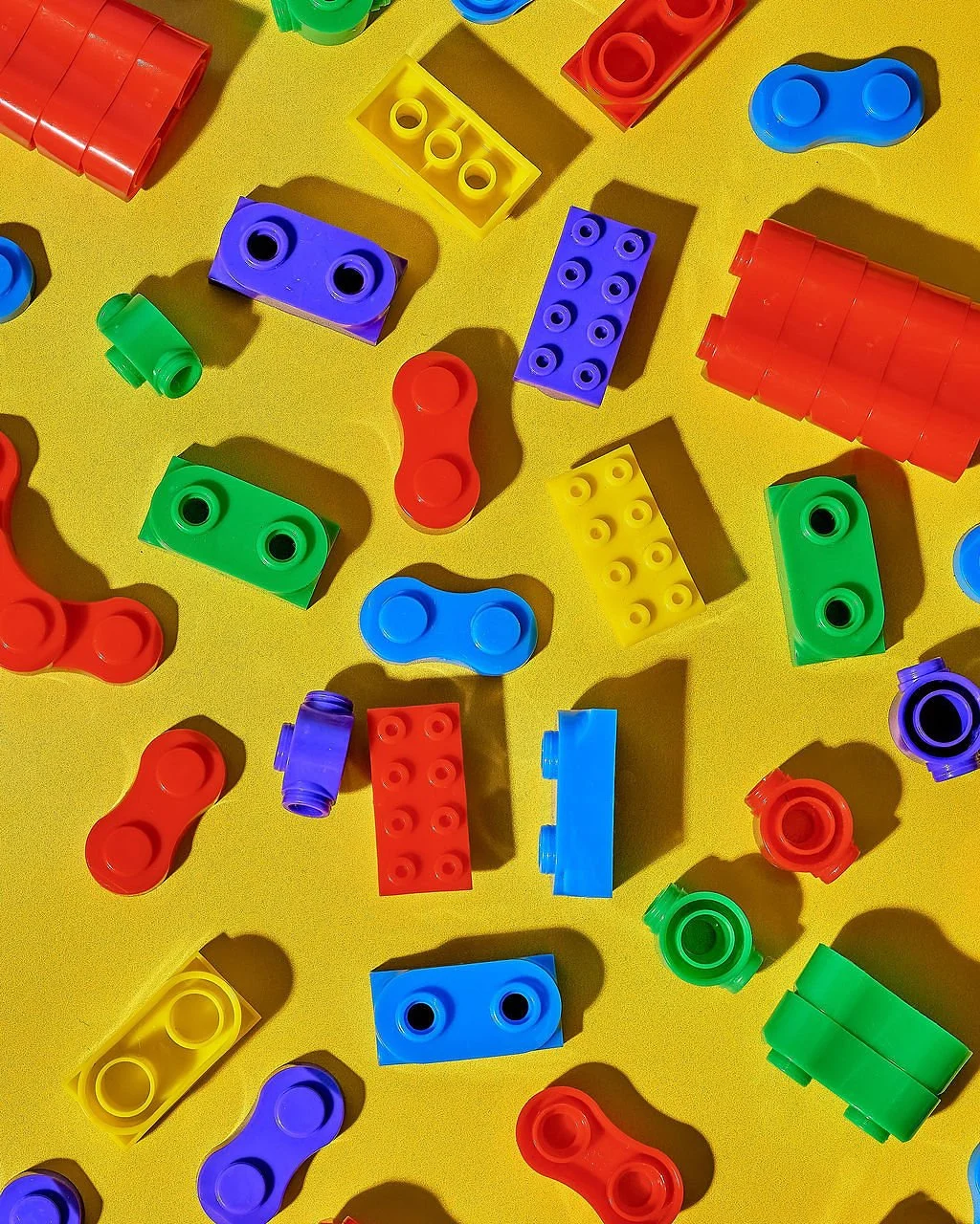 Colorful plastic building blocks scattered on a yellow surface.