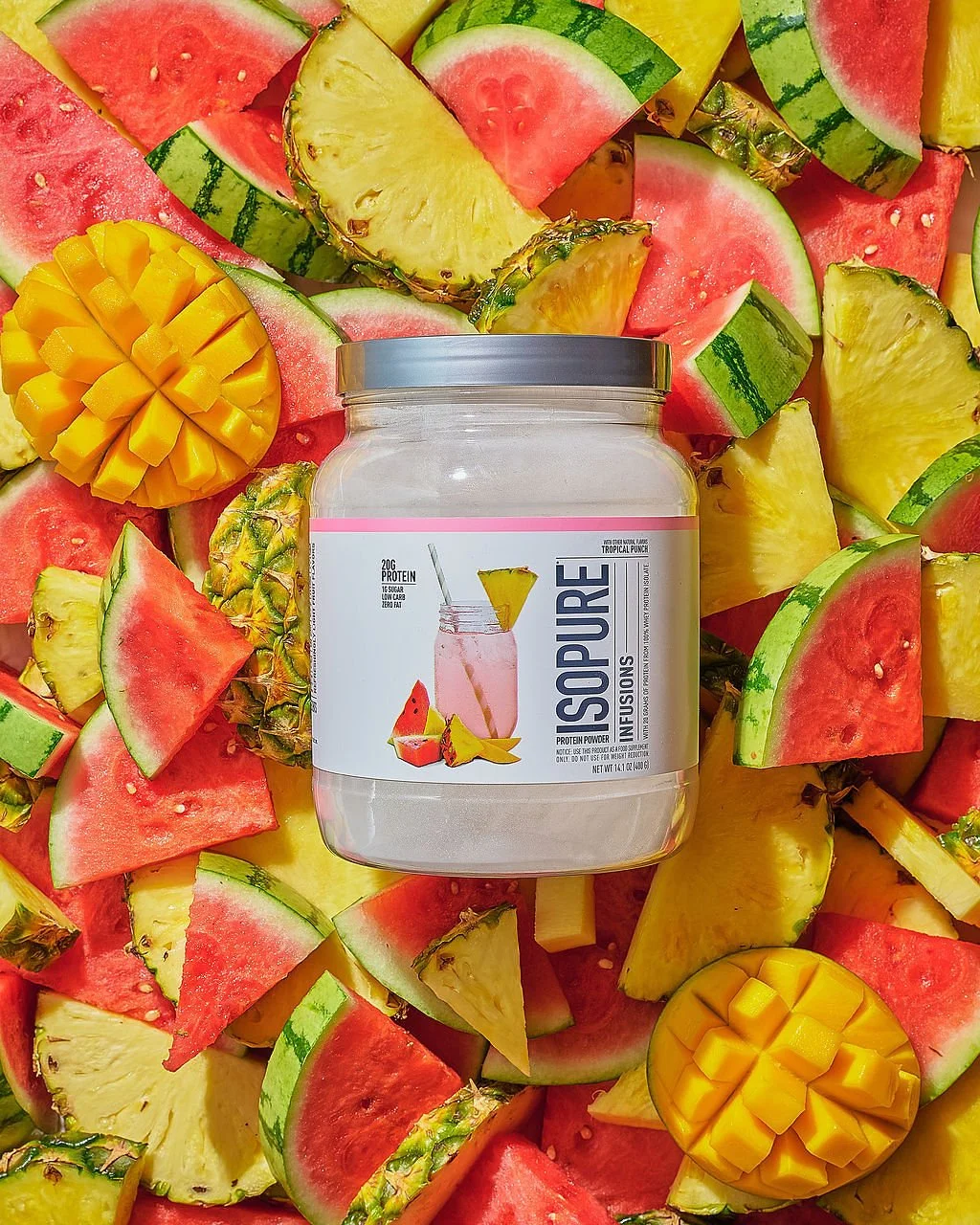 Container of protein powder labeled ISO PURE surrounded by sliced watermelon, pineapple, and mango.