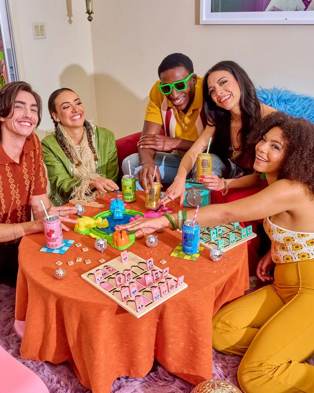 A group of six diverse friends playing a board game at a party, smiling and having fun, with snacks and drinks on the table.