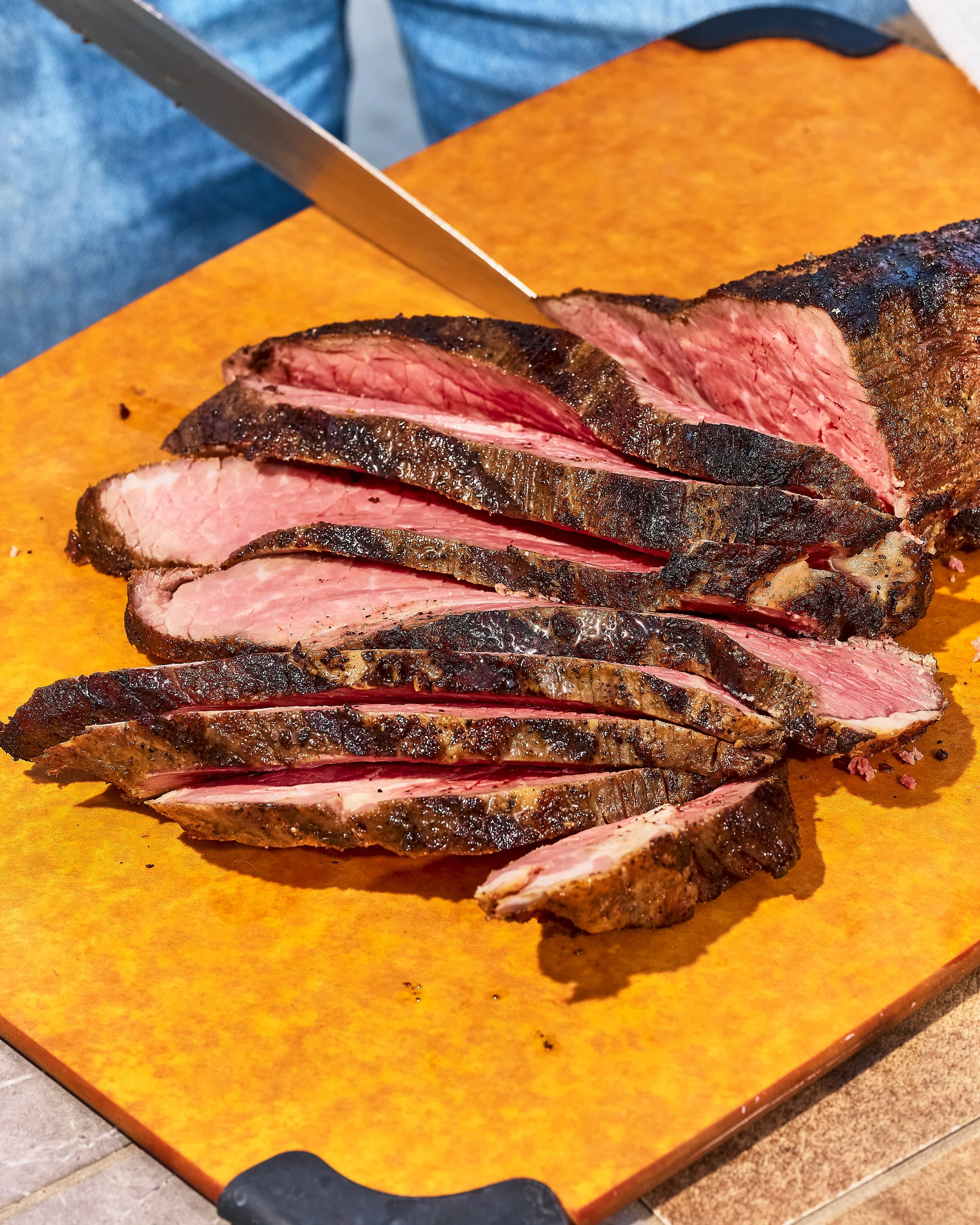 Slices of grilled steak on a wooden cutting board.