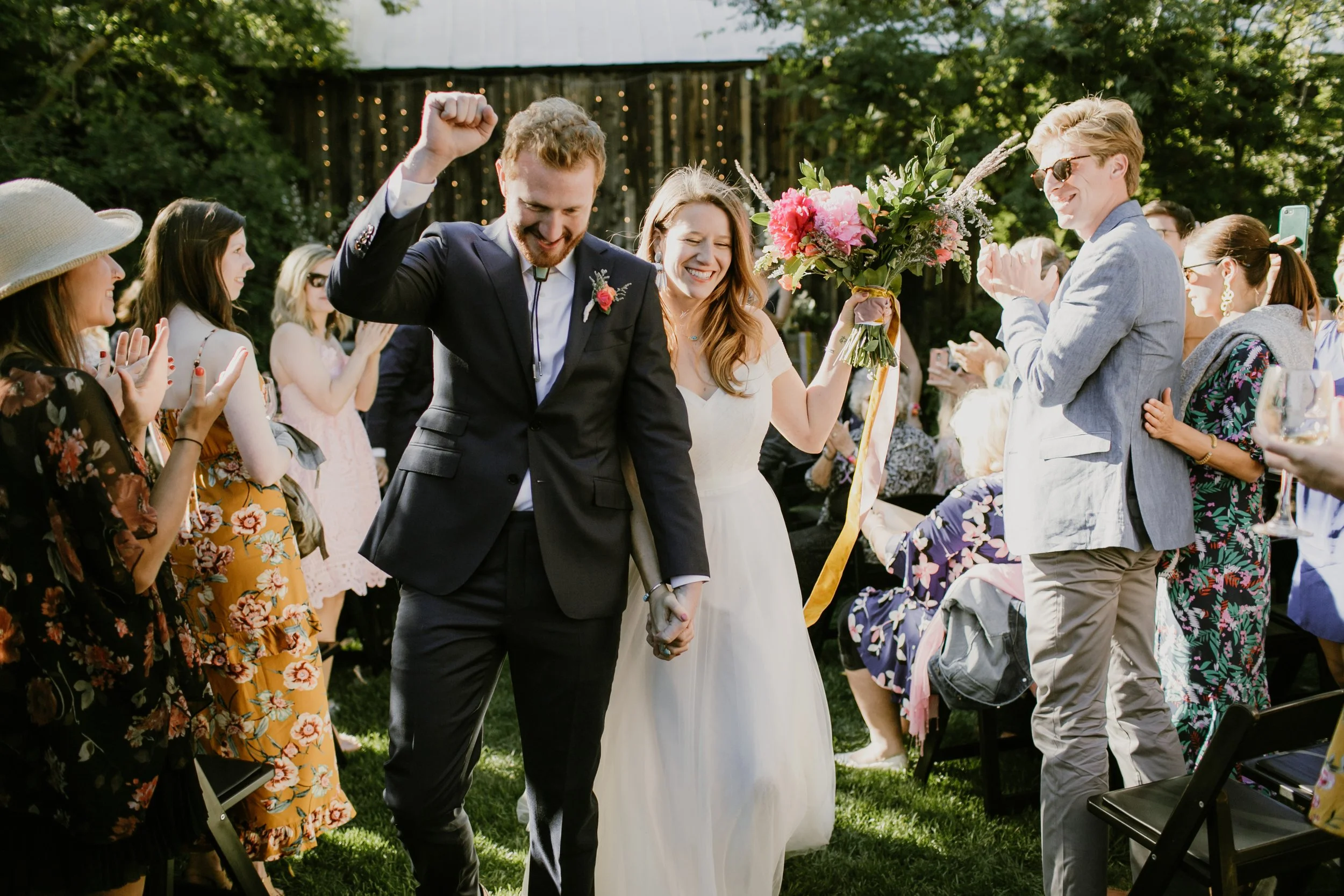 An image of a bride and groom exiting their wedding ceremony at StoneHouse101 in Roslyn, Washington. StoneHouse101 is an intimate indoor outdoor events venue in Roslyn, Washington, hosting weddings, birthdays, anniversaries, and more near Cle Elum, W