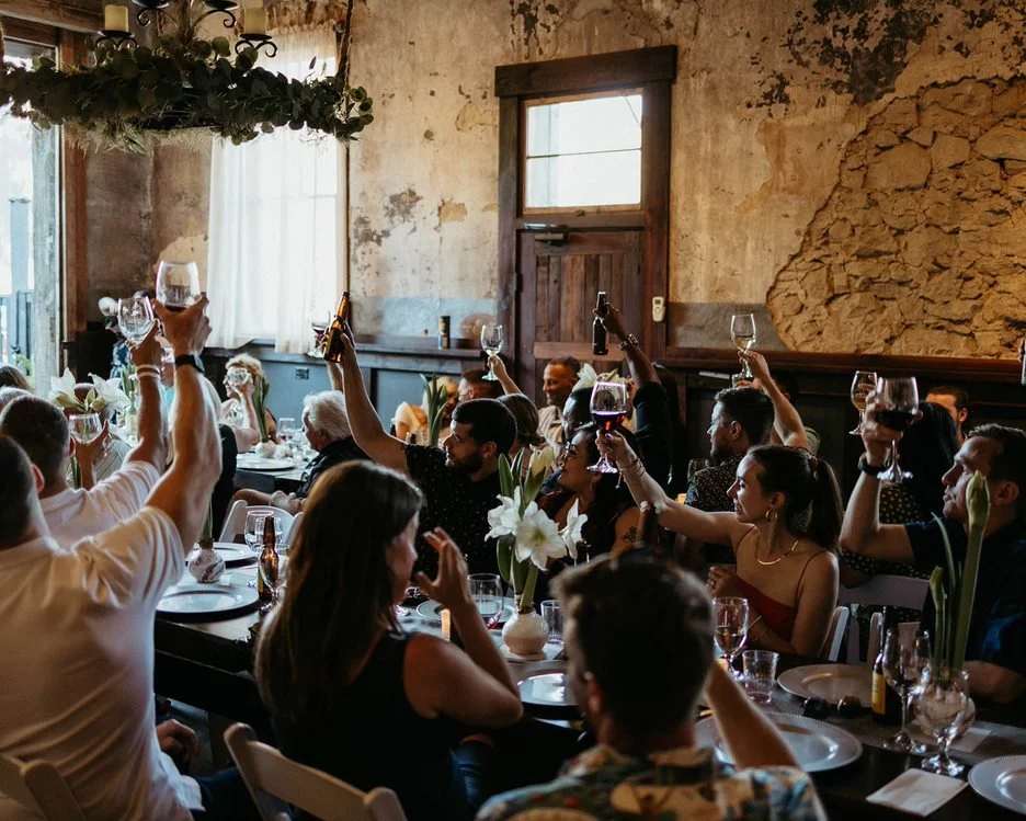 An image of guests raising a glass at an indoor celebration at StoneHouse101 Events Venue. StoneHouse101 is an intimate indoor outdoor events venue in Roslyn, Washington, hosting weddings, birthdays, anniversaries, and more near Cle Elum, WA.