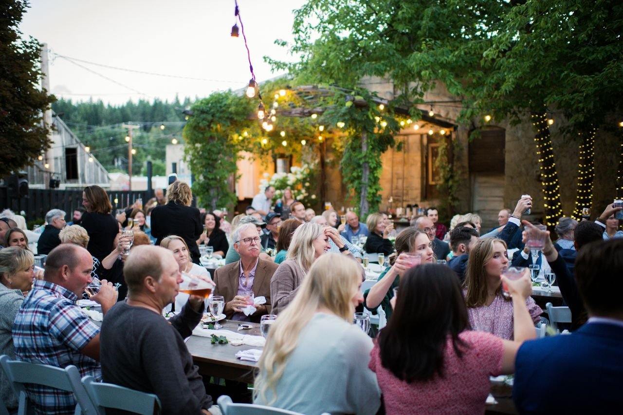 An image of guests sitting at their tables for an outdoor event at StoneHouse101. StoneHouse101 is an intimate indoor outdoor events venue in Roslyn, Washington, hosting weddings, birthdays, anniversaries, and more near Cle Elum, WA.