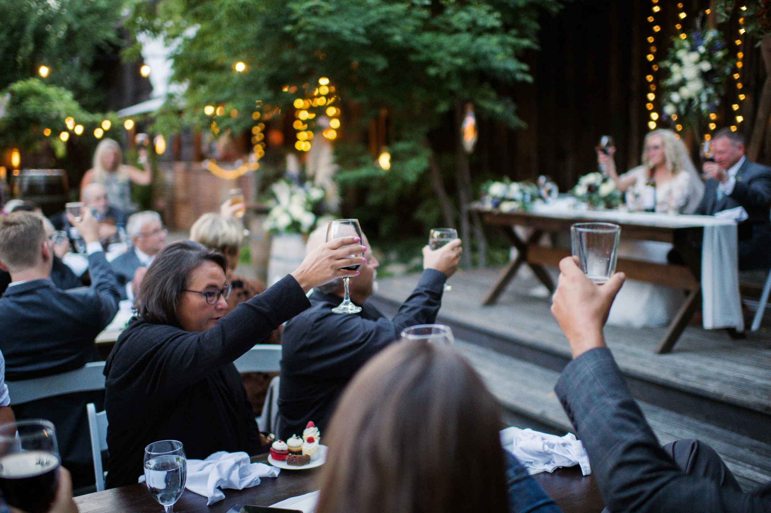 An image of guests raising their glasses at a wedding at StoneHouse101. StoneHouse101 is an intimate indoor outdoor events venue in Roslyn, Washington, hosting weddings, birthdays, anniversaries, and more near Cle Elum, WA.
