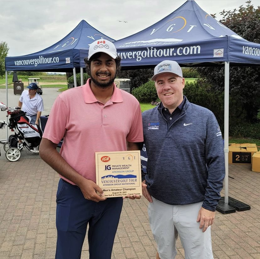 Two men smiling outdoors, one holding a certificate, standing in front of a canopy with Vancouver Golf Tour branding, and golf equipment and carts nearby.