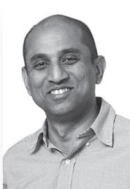 Black and white photo of a man smiling, wearing a collared shirt.