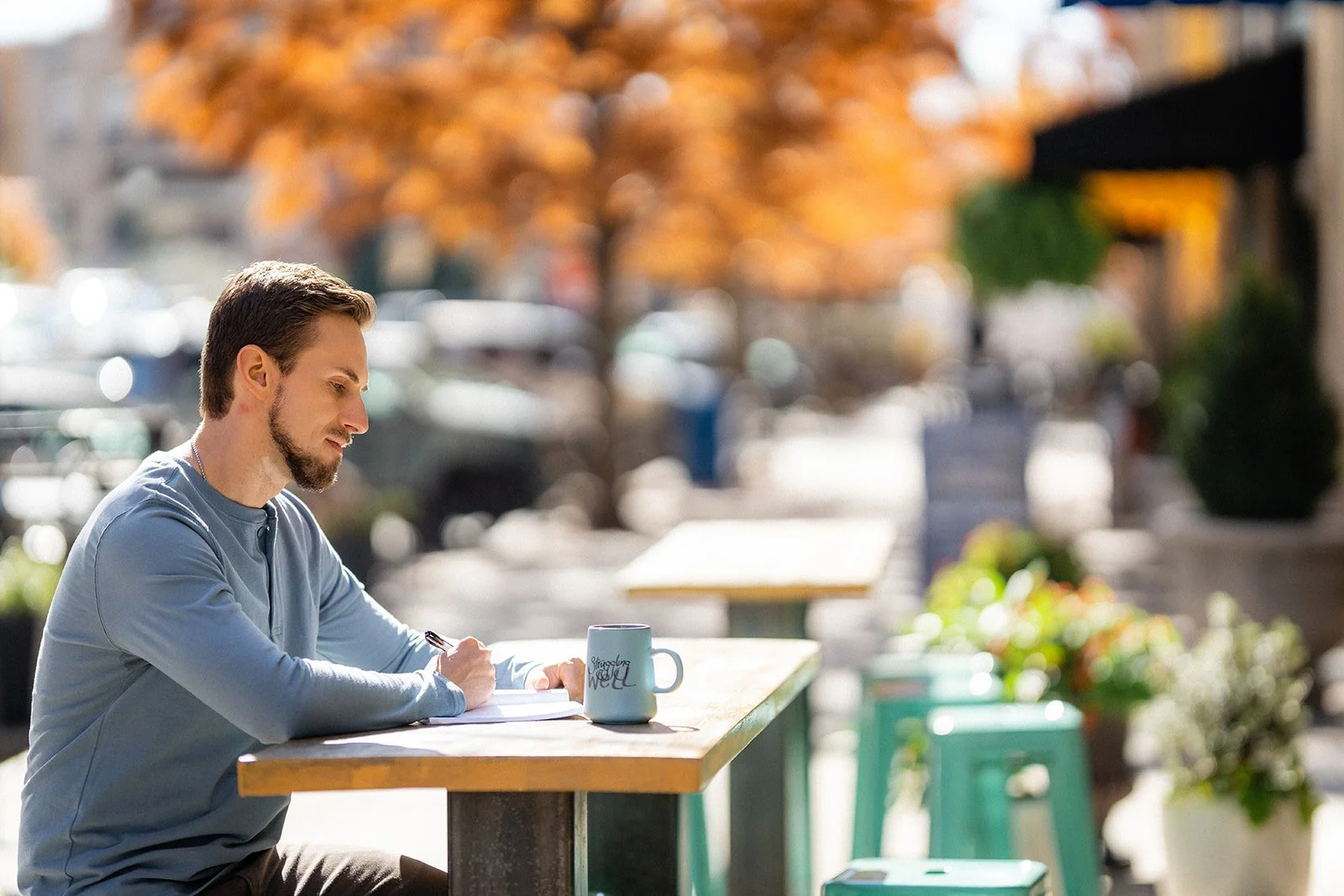 Man sitting outside, writing in a notebook.