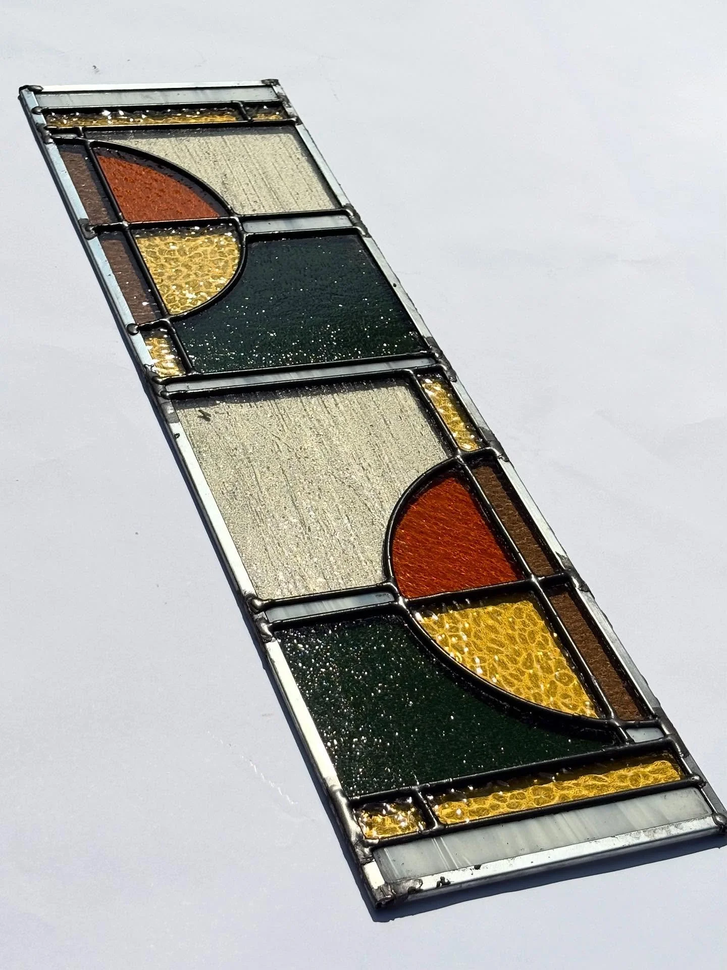 A funky 26x7 panel for a kitchen window in High Park! The panel contains opaque white, gold, cream and dusty brown glass to match their countertops, with green and orange glass to match their furniture. Installing this week!

#stainedglasstoronto #hi