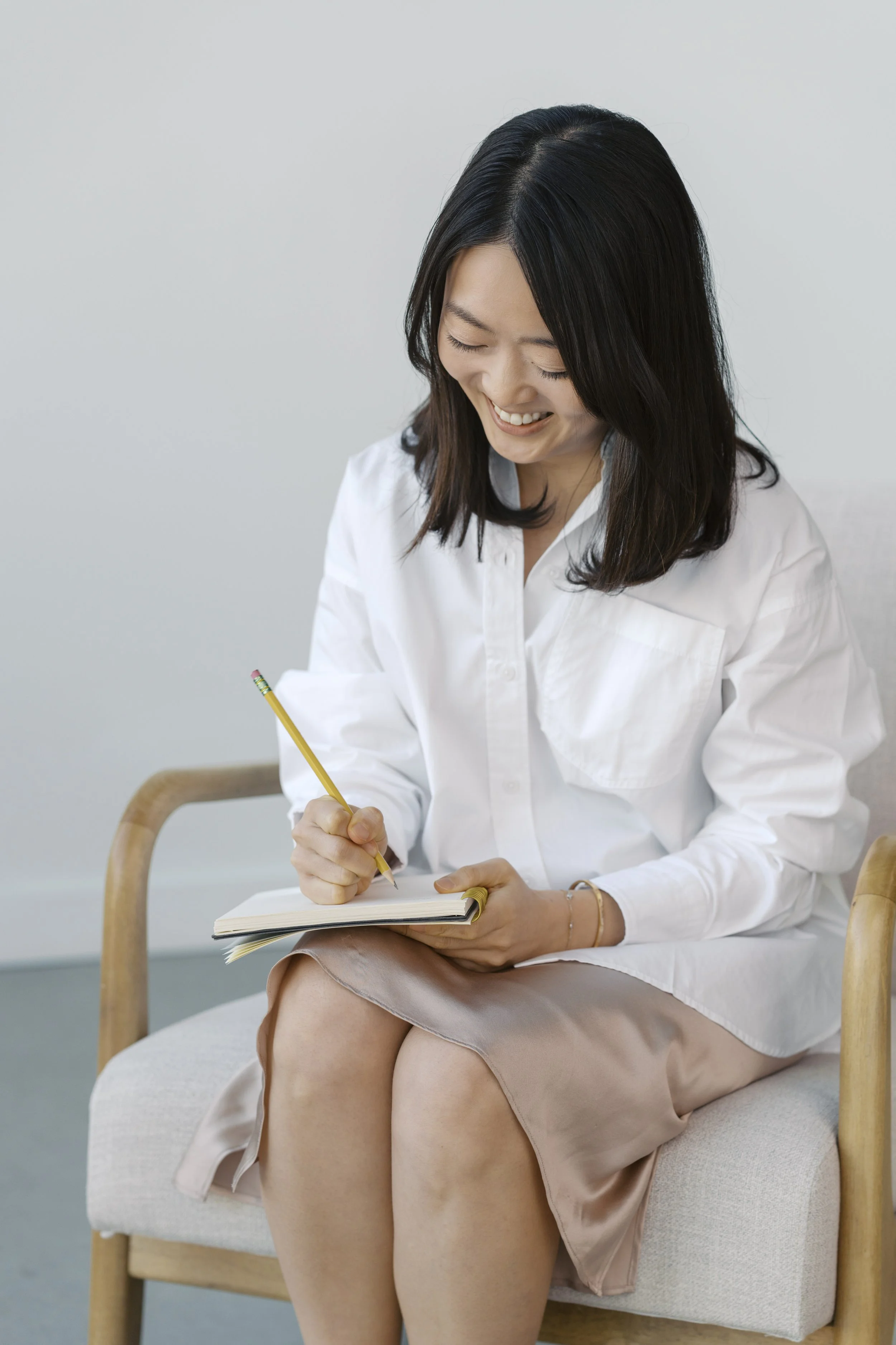 Juhee writing in a journal, taking thoughtful notes for an upcoming inner child therapy group session.