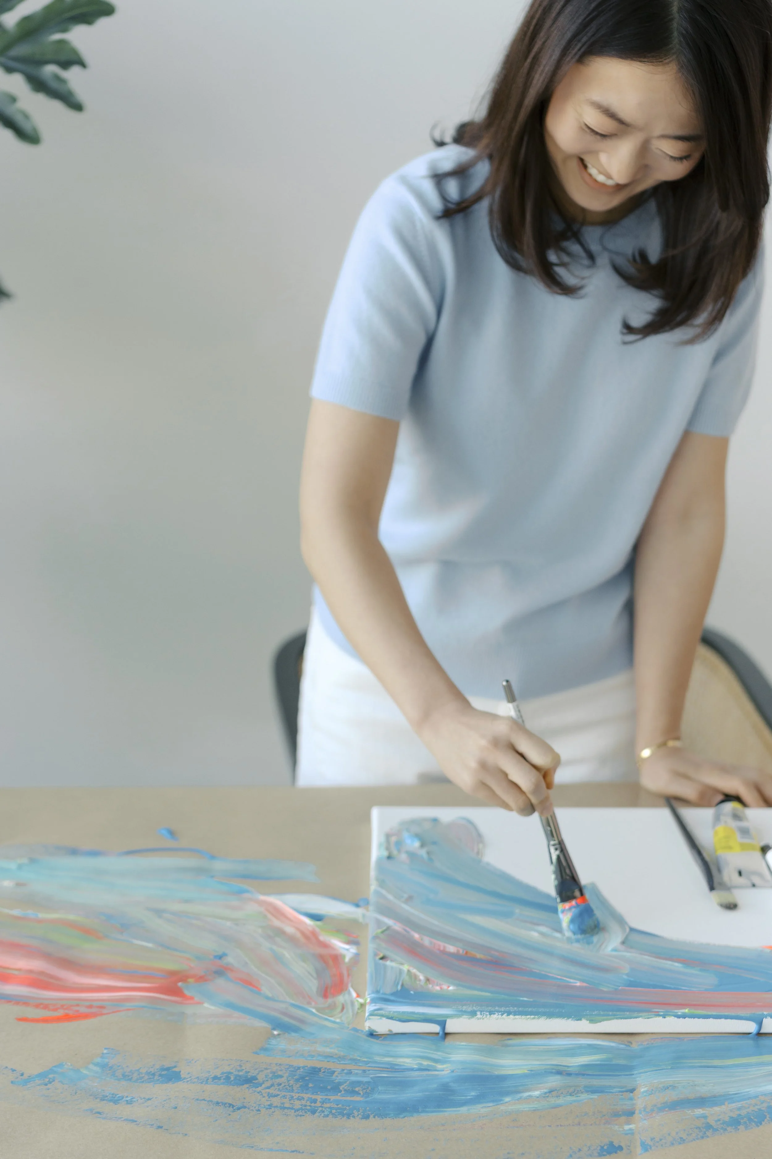 Close-up of Juhee painting with a brush during an inner child healing art therapy session.