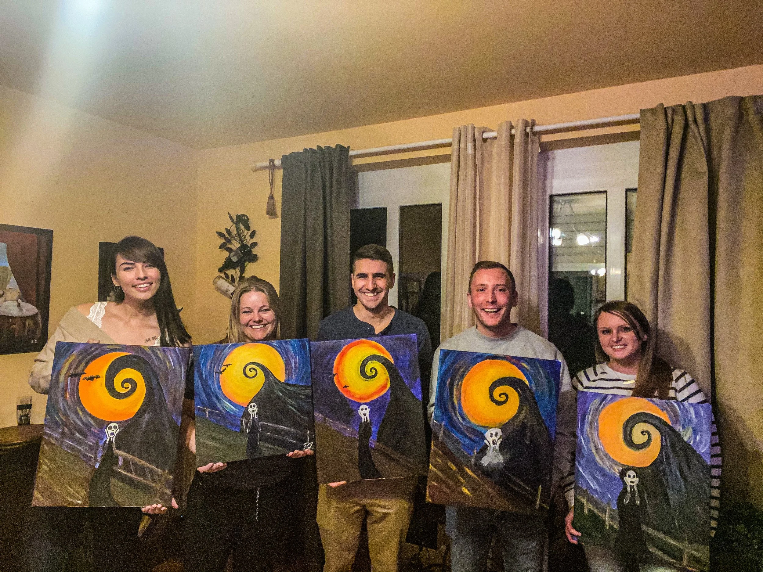 Five people standing indoors at night holding paintings inspired by Van Gogh's Starry Night with a yellow and orange swirling moon and a dark, swirling sky.