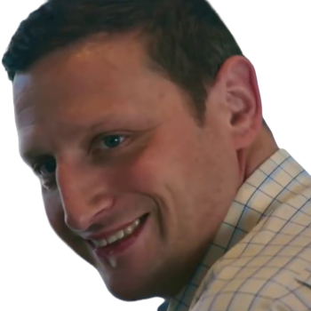 Close-up of a man smiling and looking to the side, wearing a plaid shirt.