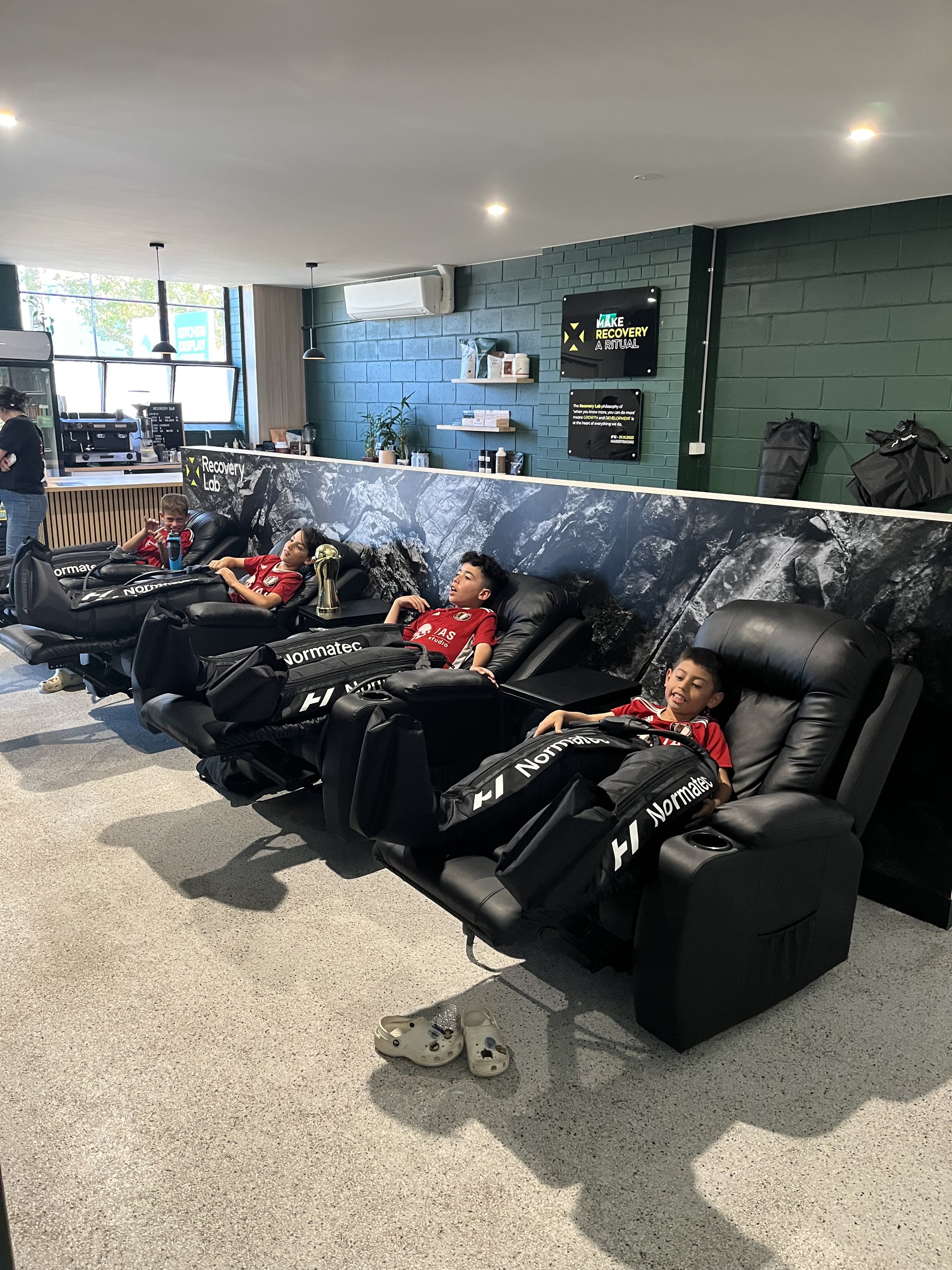 Group recovery session at Recovery Lab Maribyrnong featuring compression massage chairs in the recovery lounge.