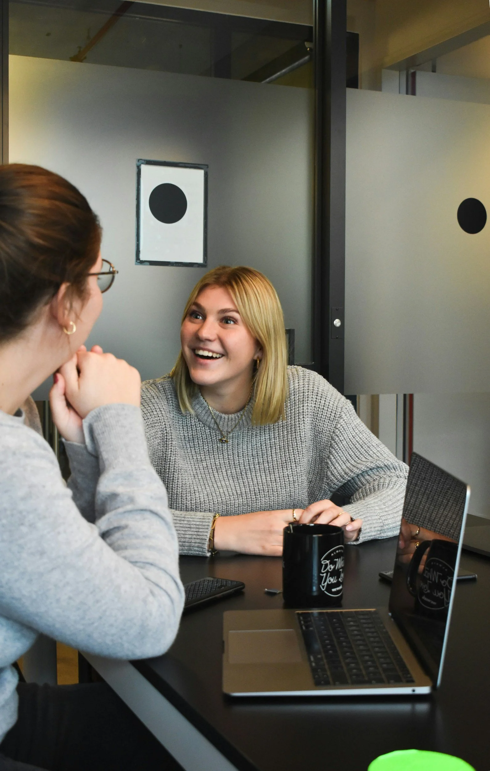 Two women sitting at a table in conversation, representing supportive guidance and personalized healthcare navigation.