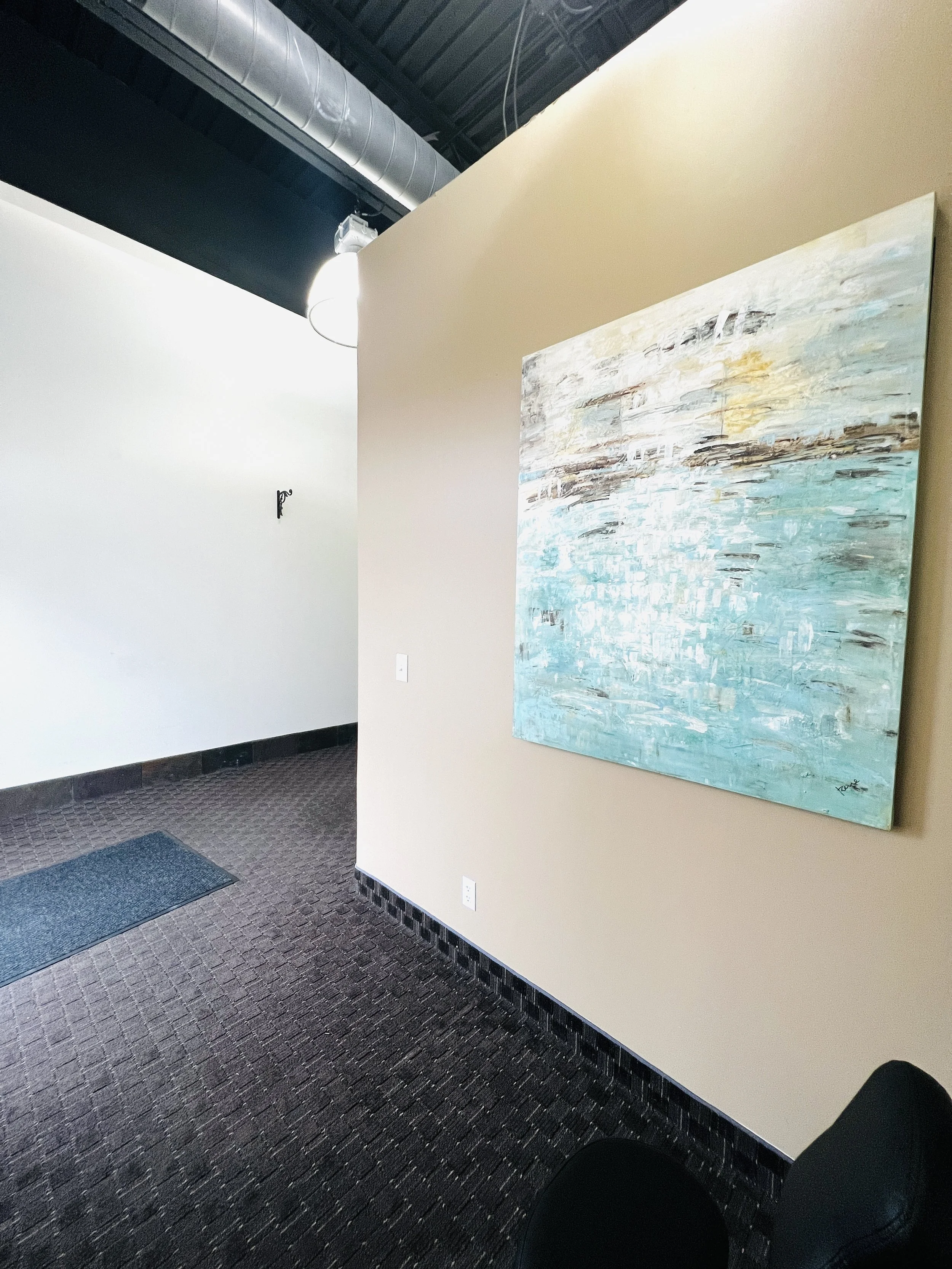 Reception area of a spa or massage center with a massage advertisement on the window, a white sofa, a beige rug, and a wooden reception desk.