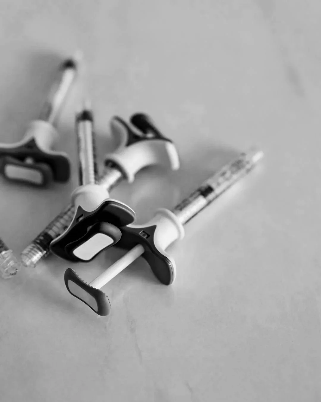 Black and white photo of syringes and injection equipment on a flat surface.