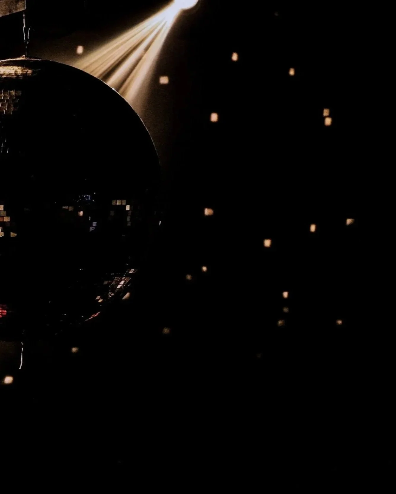 Disco ball reflecting light and small light spots on a dark background.