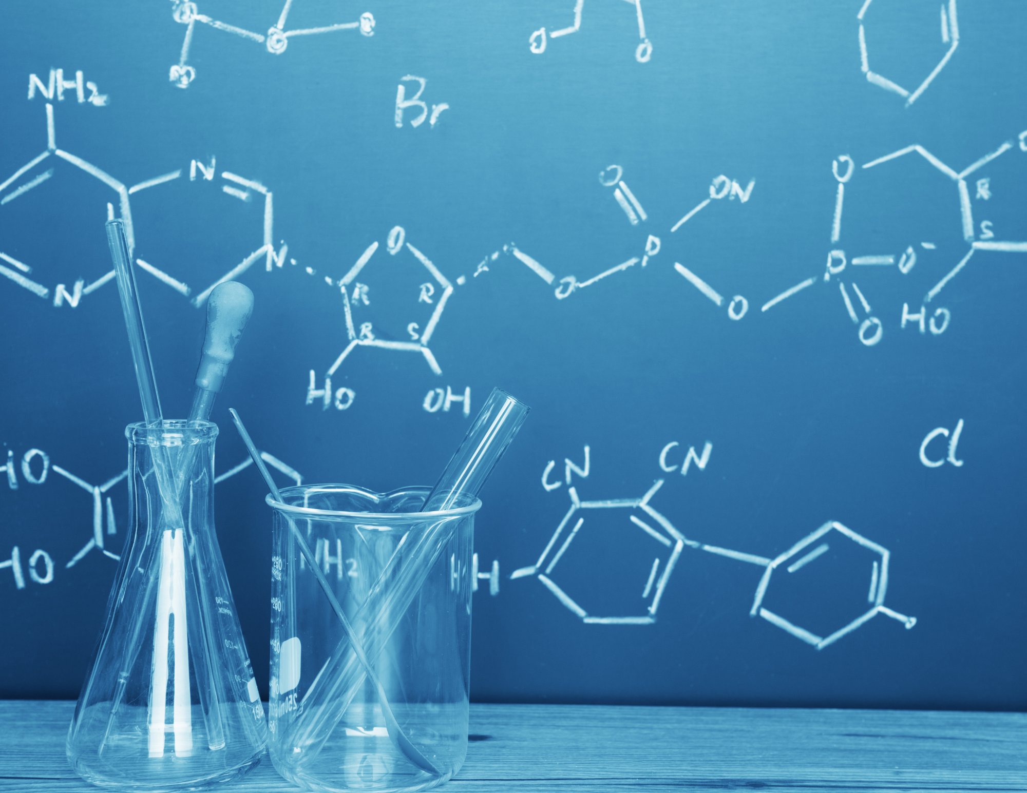 A chemistry laboratory scene featuring glassware and chemical formulas on a blackboard in the background.