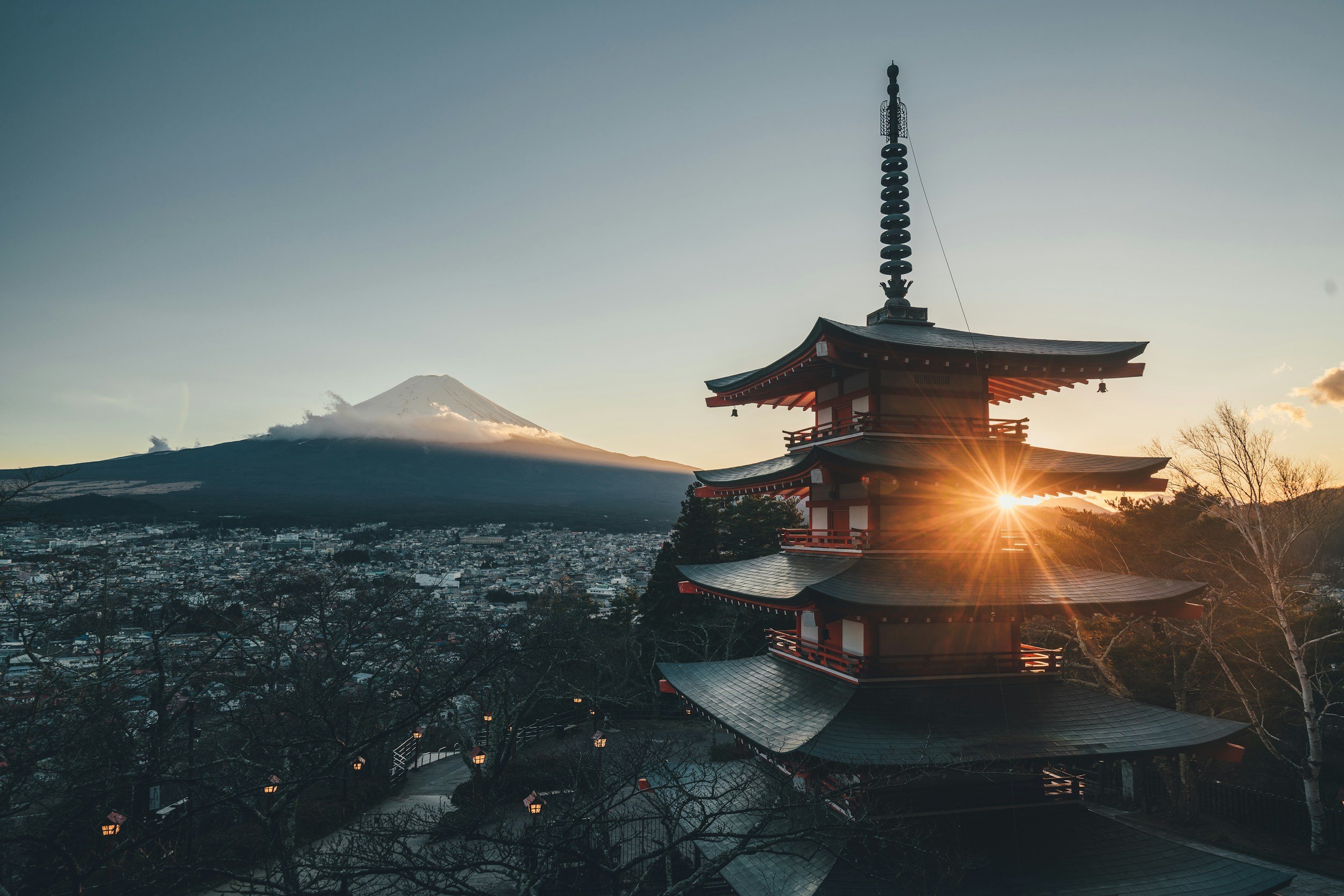 Traditional Japanese pagoda with Mount Fuji in the background at sunset or sunrise.