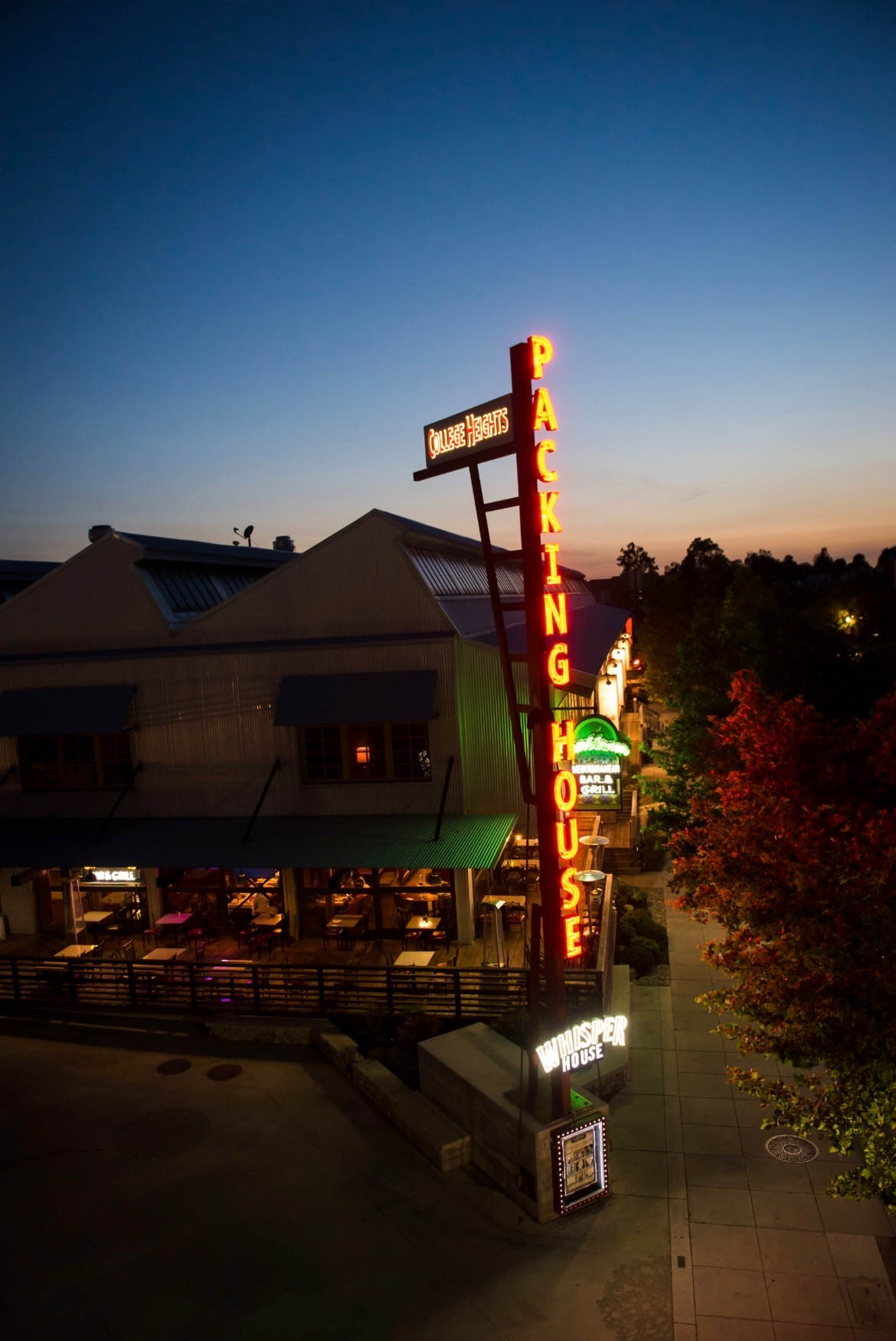 Neon sign for Packing House featuring college harvest and bar & grill at dusk