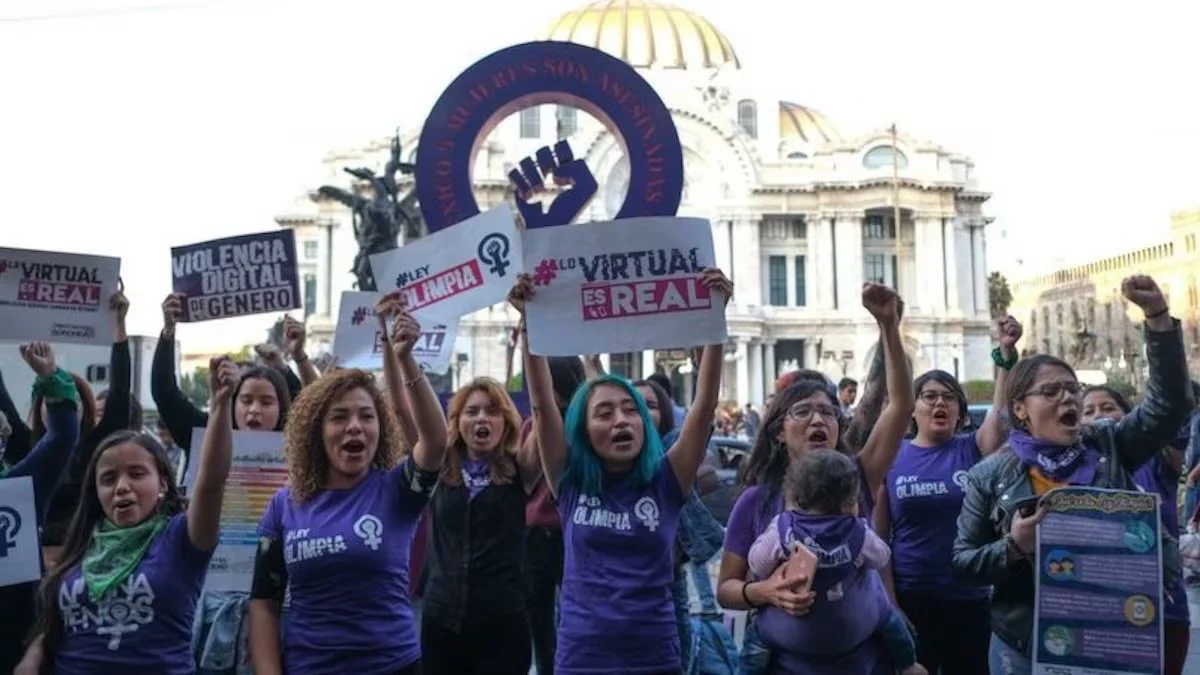 Group of women protesting with signs and raised fists in front of a government building.