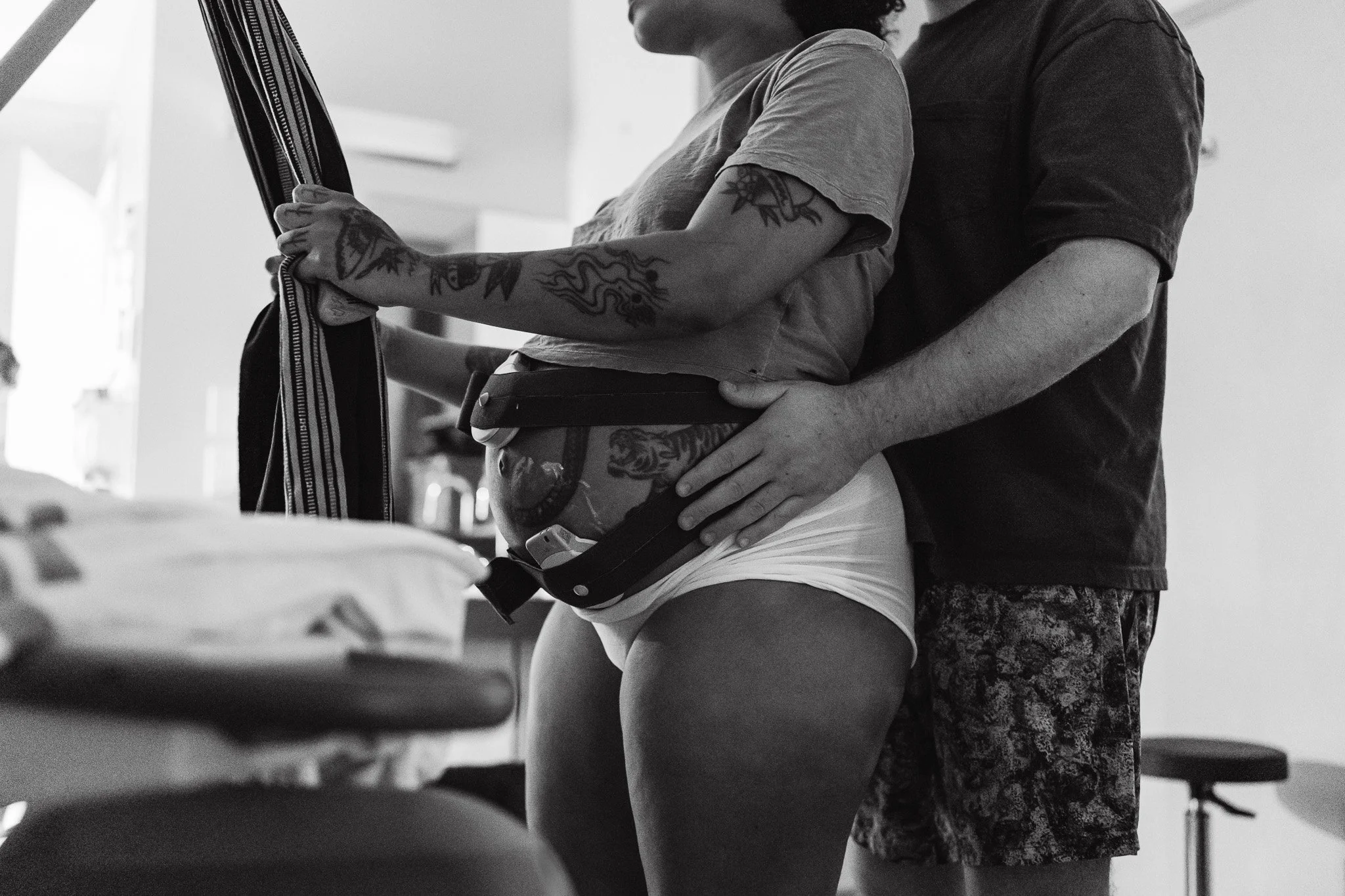 Labouring parent breathing through a surge, supported by their partner during a West Kootenays birth documented by The Birth Laine