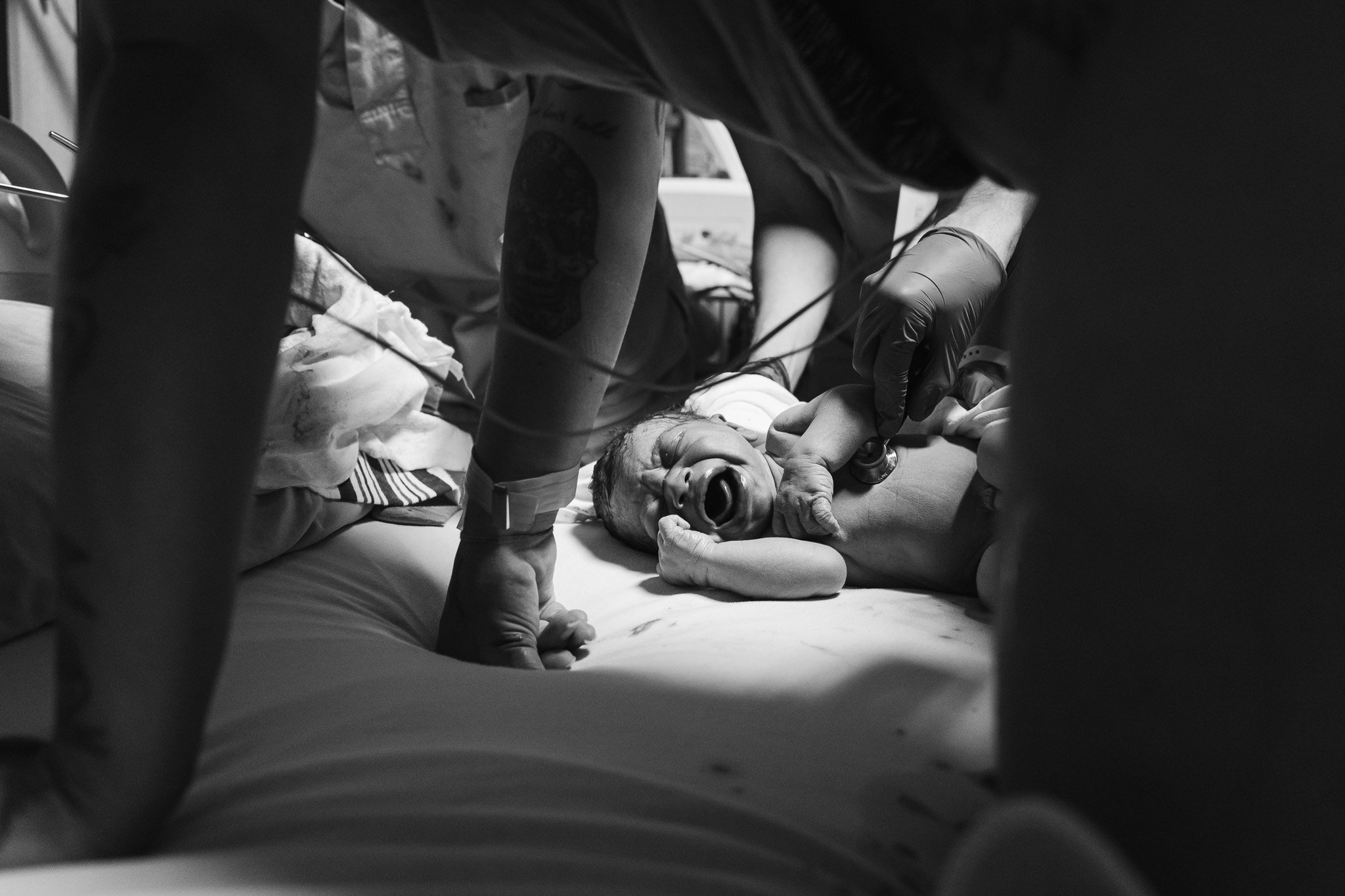 Close-up of newborn on bed moments after hospital birth — documentary birth photography in Nelson BC