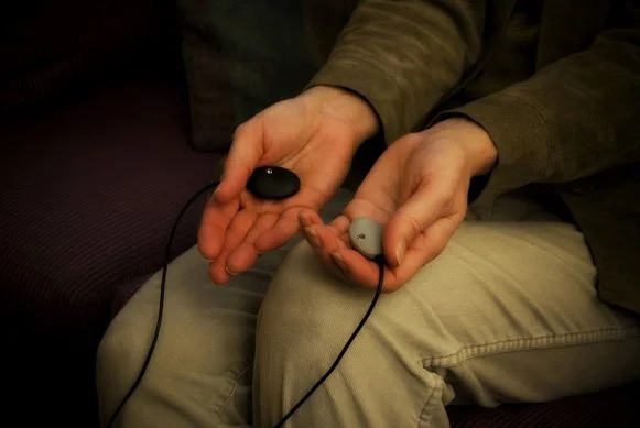 Person holding two cochlear implant processors in their hands.