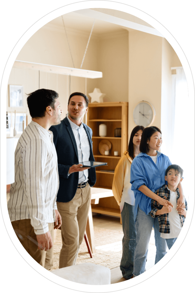 A real estate agent showing a house to a family of four inside a living room.
