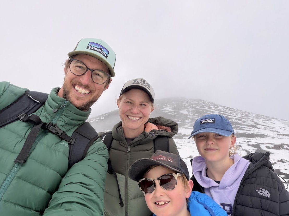 Four hikers posing on a snowy mountain with foggy weather.