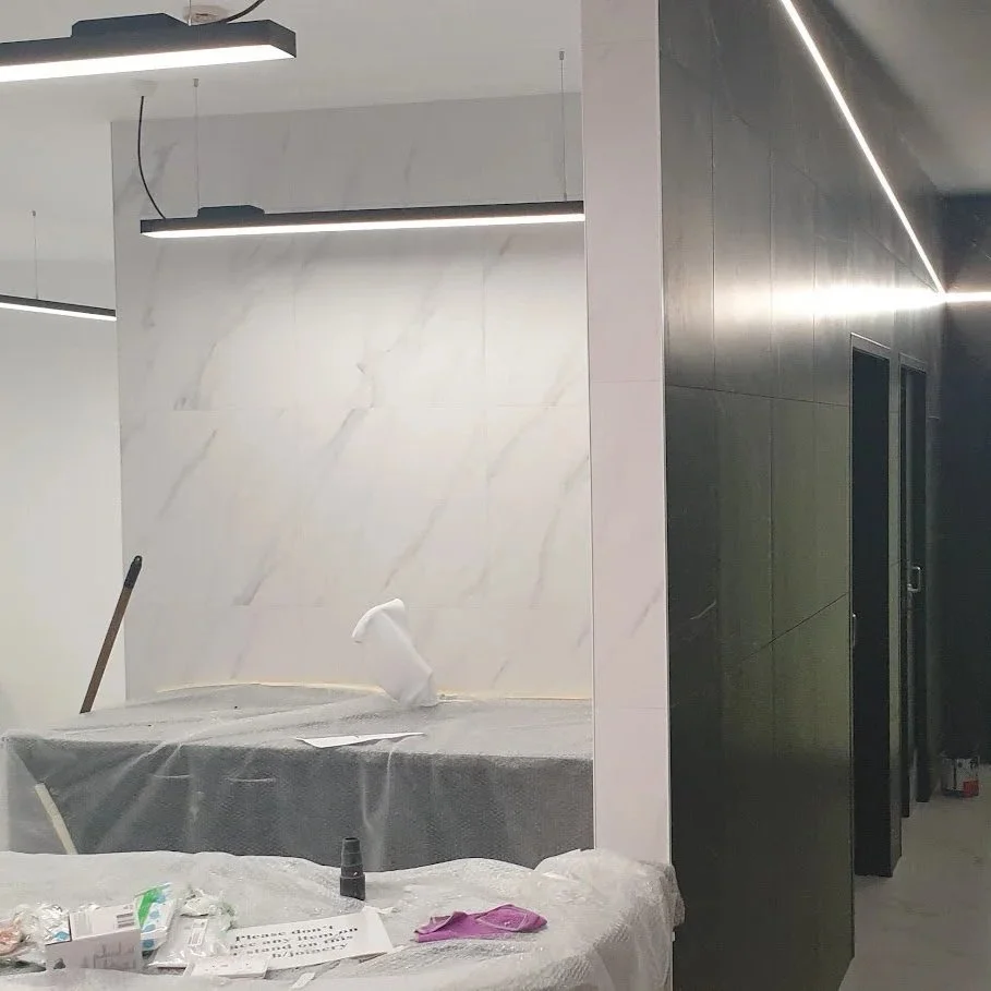 Construction or renovation area with marble wall, covered work surface, cleaning supplies, and protective plastic coverings.