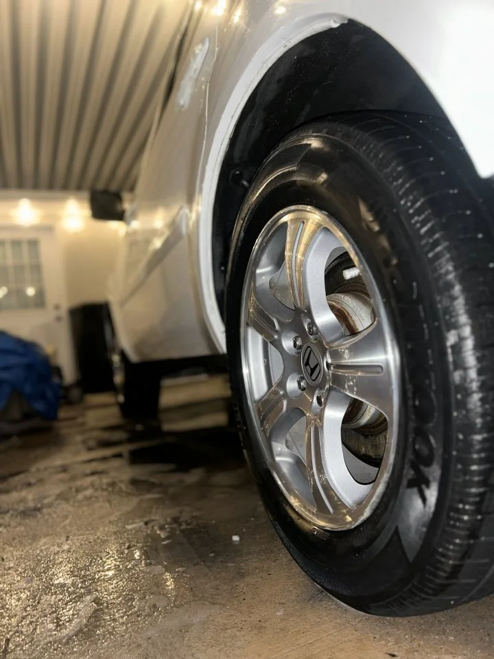 Close-up of a car wheel with a shiny alloy rim and black tire, after a deep wheel clean. This is part of the exterior detail.