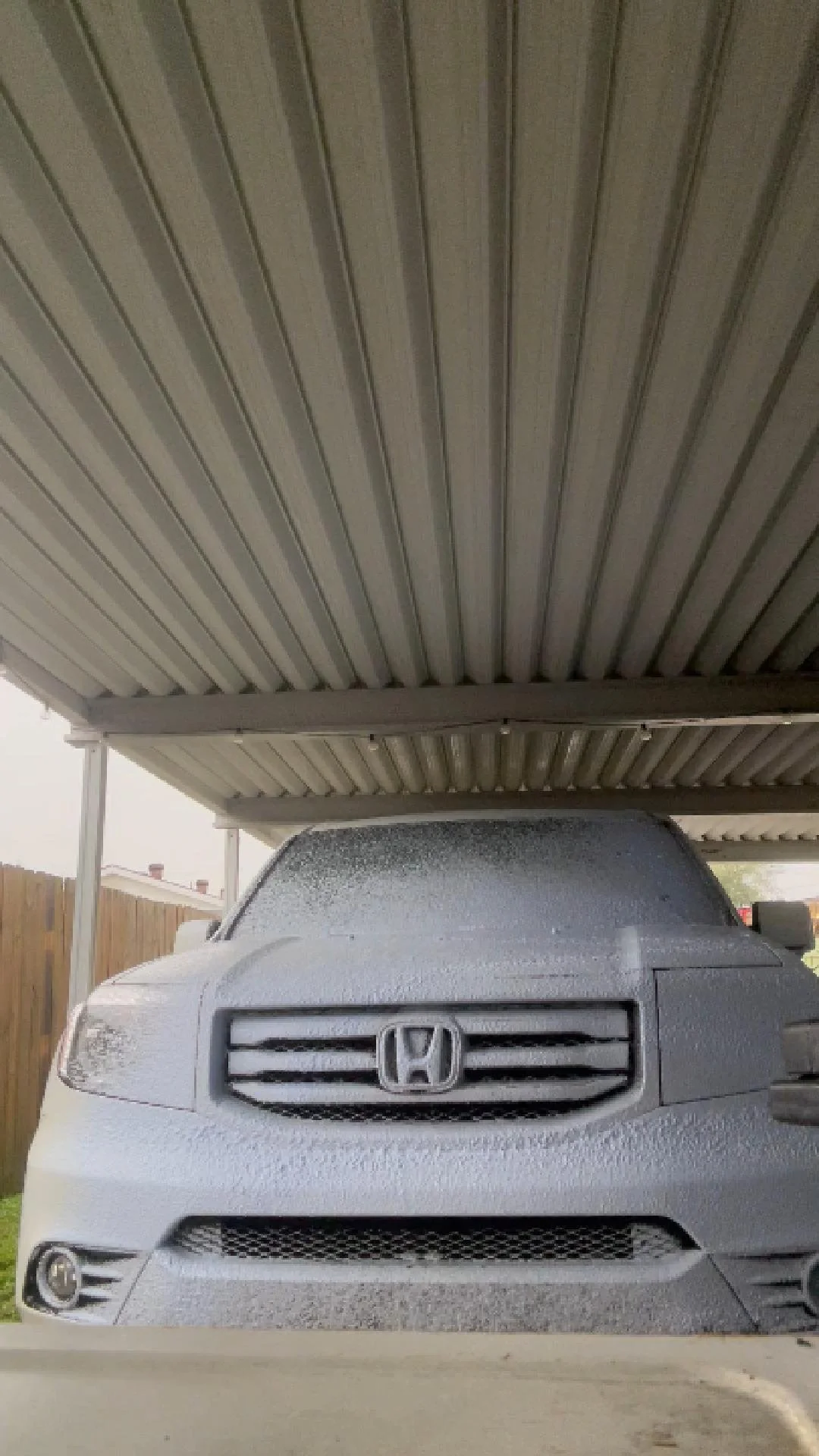 A white Honda car covered in purple snow foam during an exterior wash.
