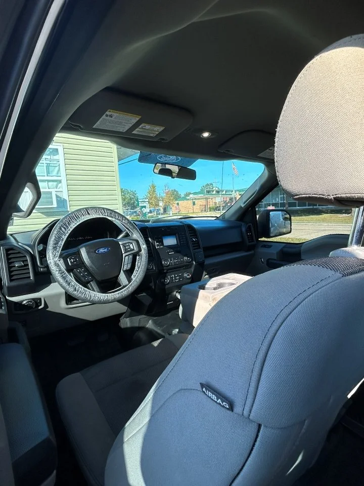 Inside view of a Ford Truck showing the front seats, steering wheel, dashboard, and a clear view of the outside through the windshield after an interior detail | Pro Purple Mobile Detailing