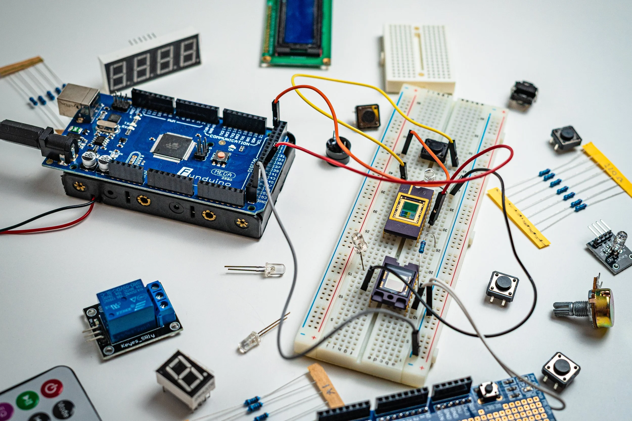 Electronics project setup with Arduino, breadboards, sensors, resistors, switches, and wires on a white table.