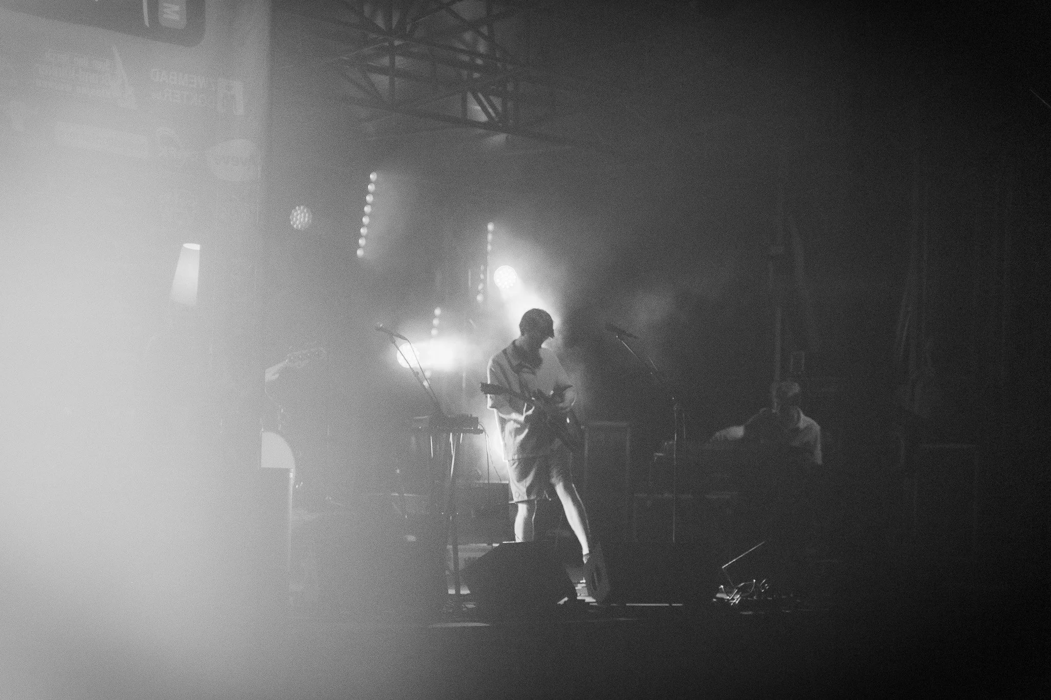 A person on stage holding a microphone, with stage lights shining behind them, creating a silhouette effect during a concert or performance.