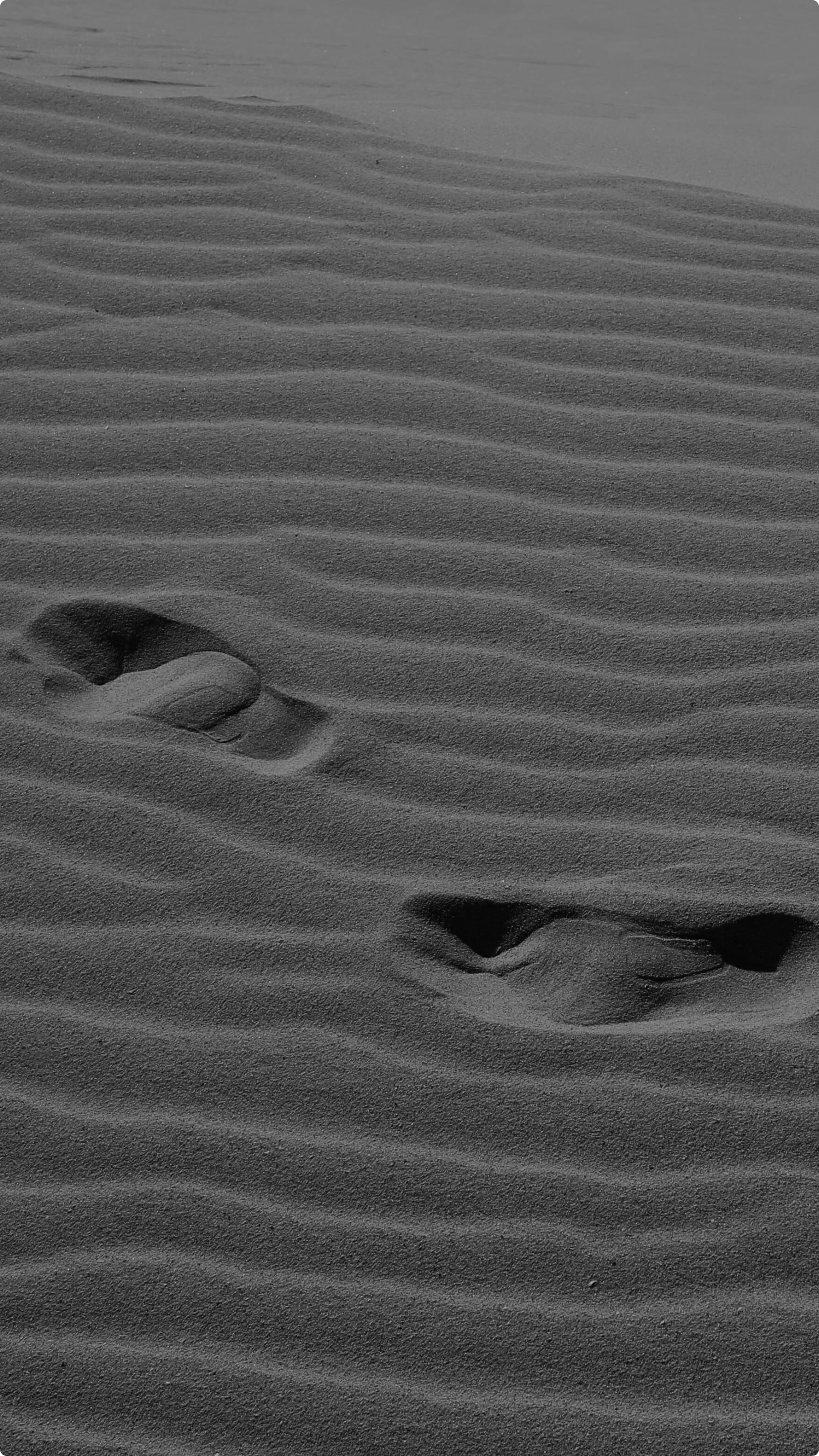 Footprints in sand with wind-created ripples.