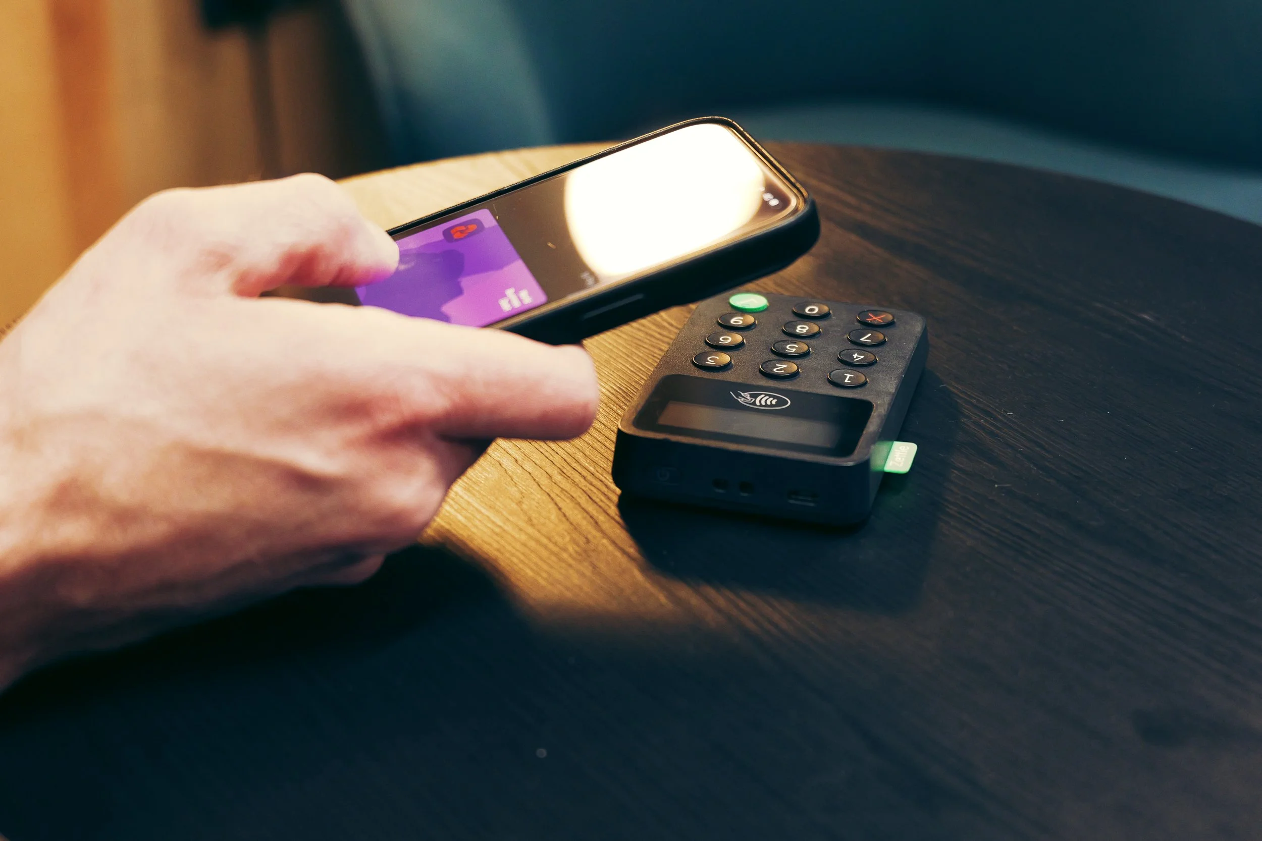 Person holding a credit card with a laptop on the table.