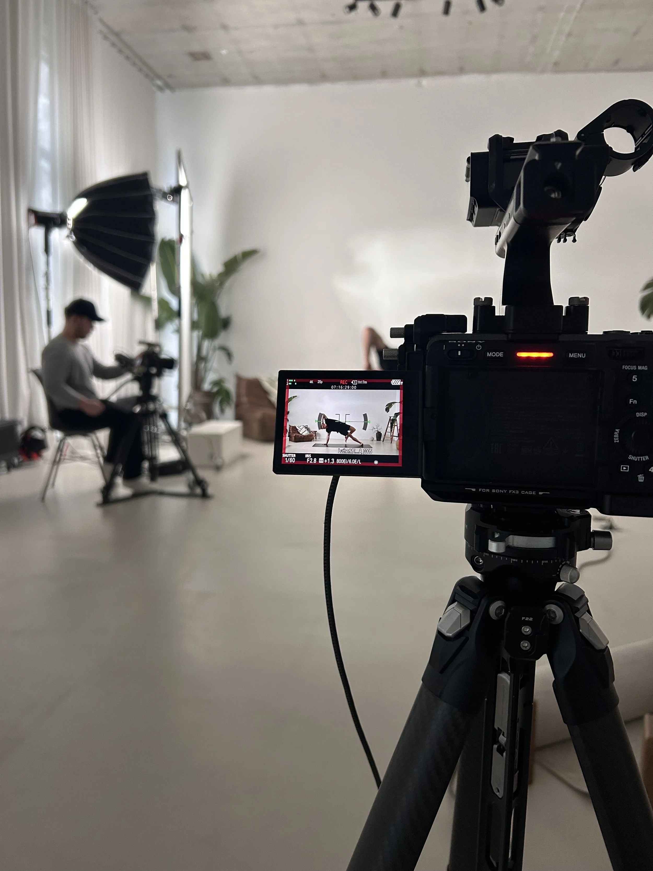 Professional fitness class filming setup with camera, lighting and instructor recording a workout session in a studio