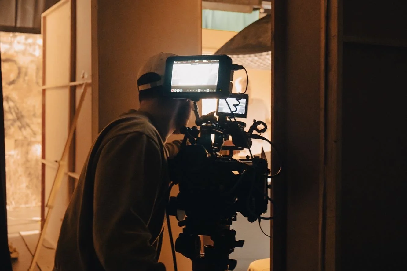 Camera operator filming a fitness instructor with a professional video setup, used for creating on-demand workout content.