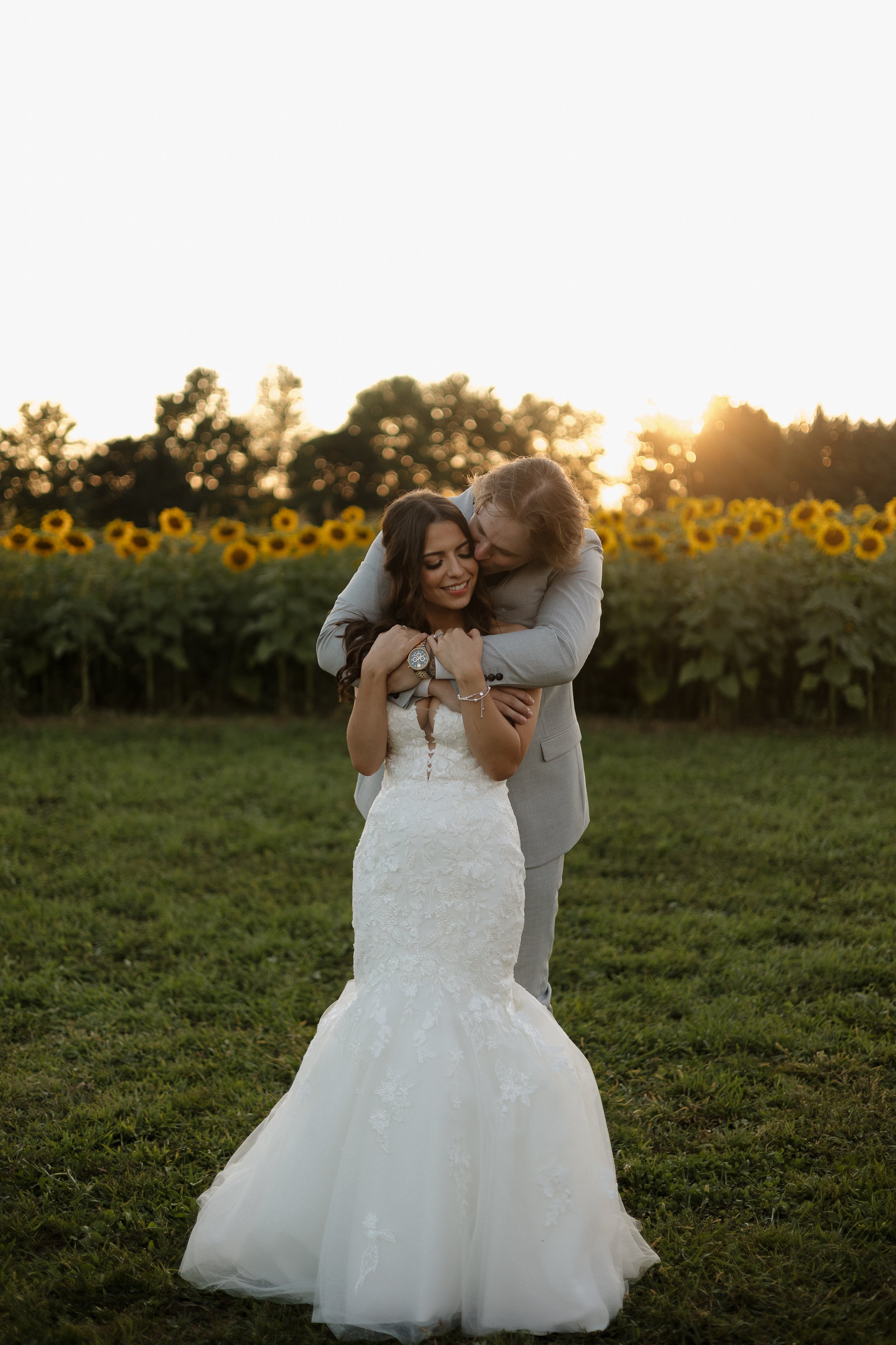 Bride and groom embracing at sunset in sunflower fields, Barn Swallow Fields wedding, Ontario wedding photography by James and Alyson Photography