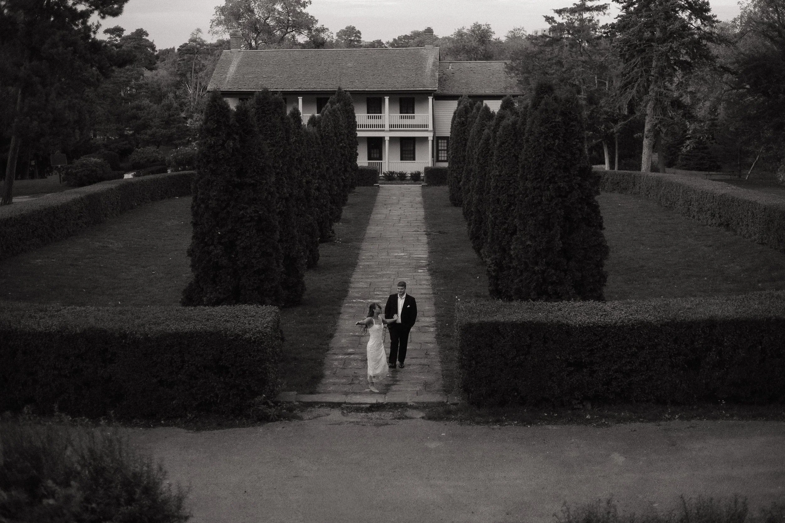 Couple having fun spinning and walking down the path at Battlefield House and Museum in Hamilton Ontario