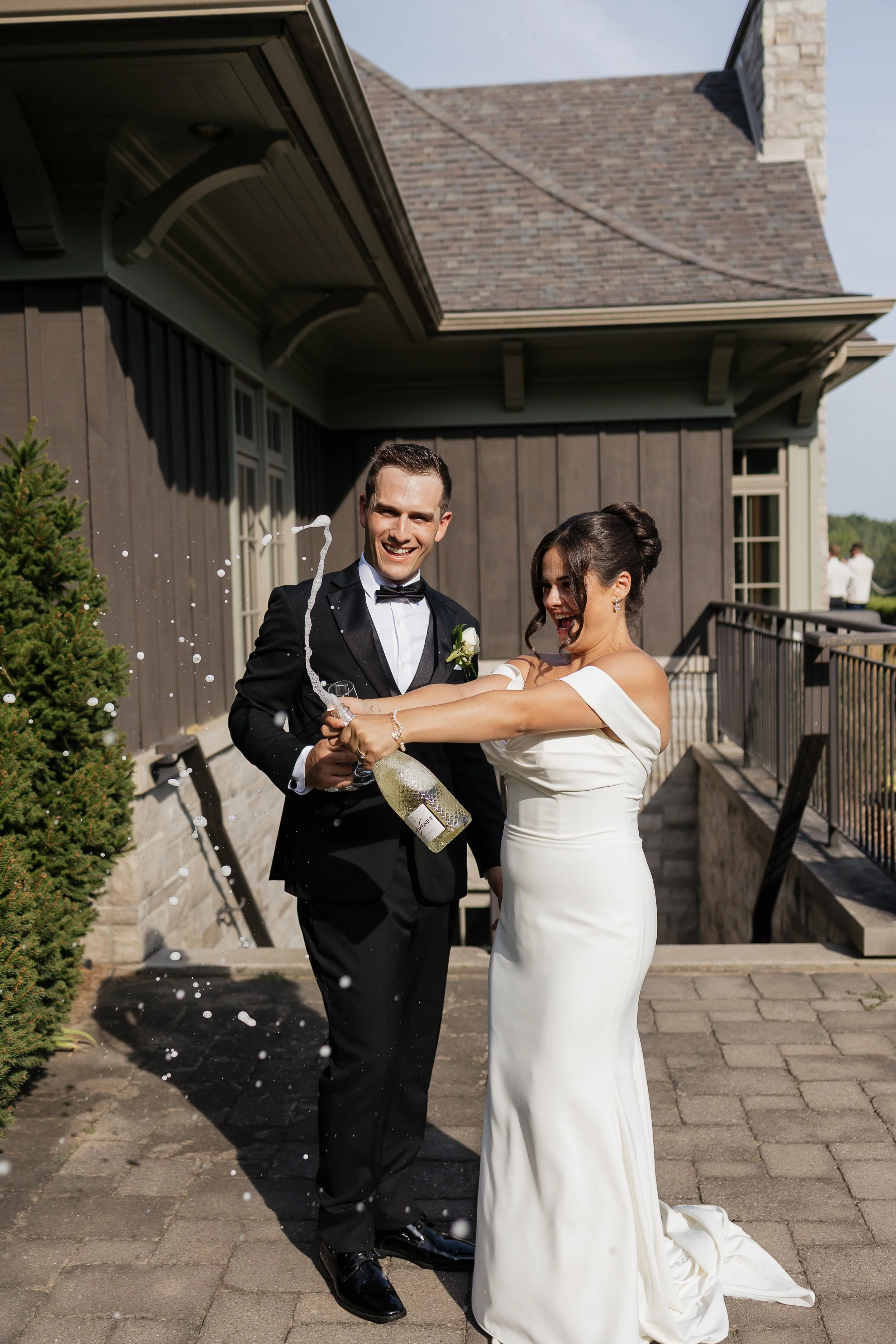 Bride and groom popping champagne together after their wedding ceremony, photographed by James & Alyson Photography