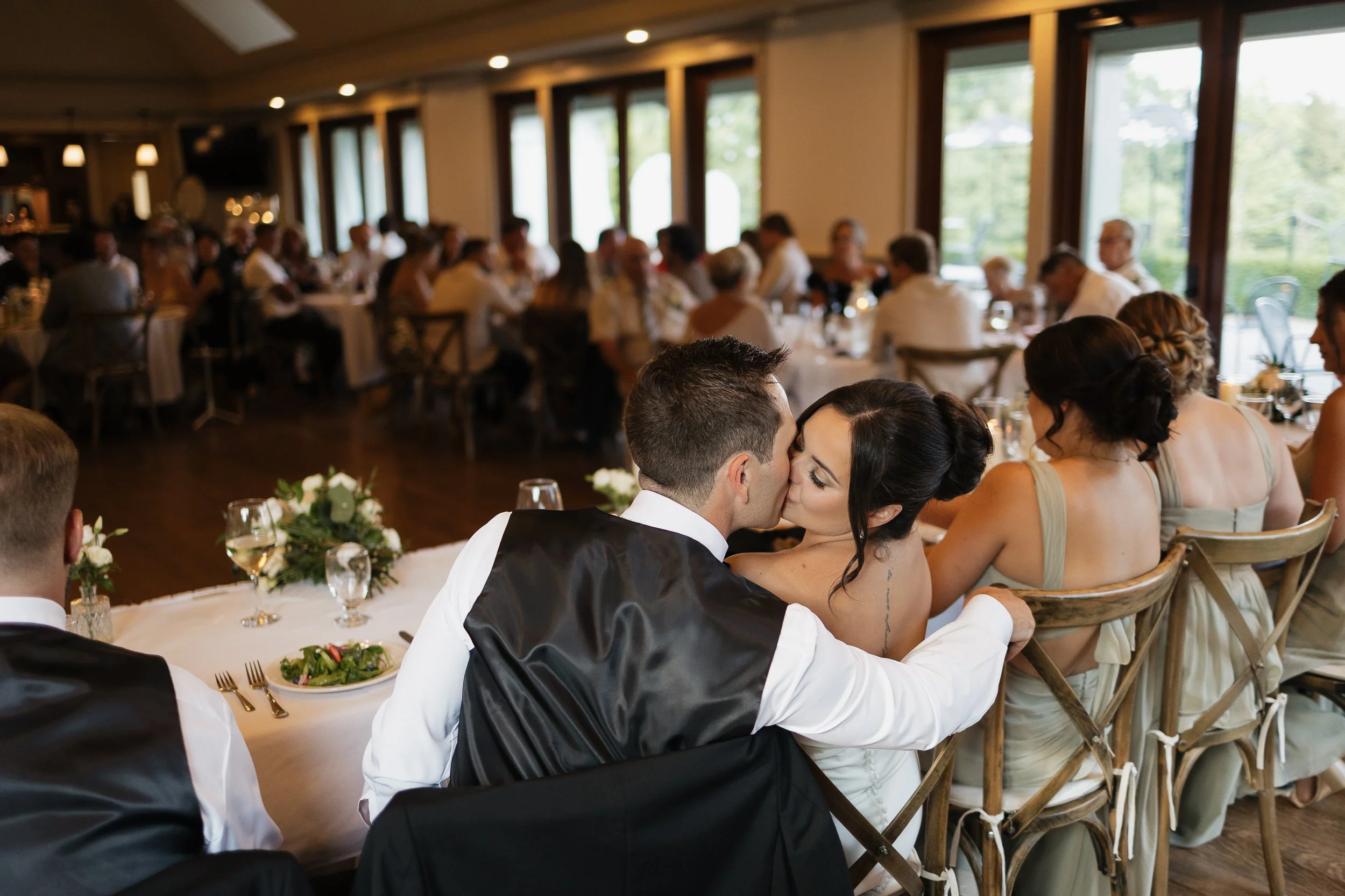 bride and groom kissing at the head table, Ontario wedding photography by James and Alyson Photography